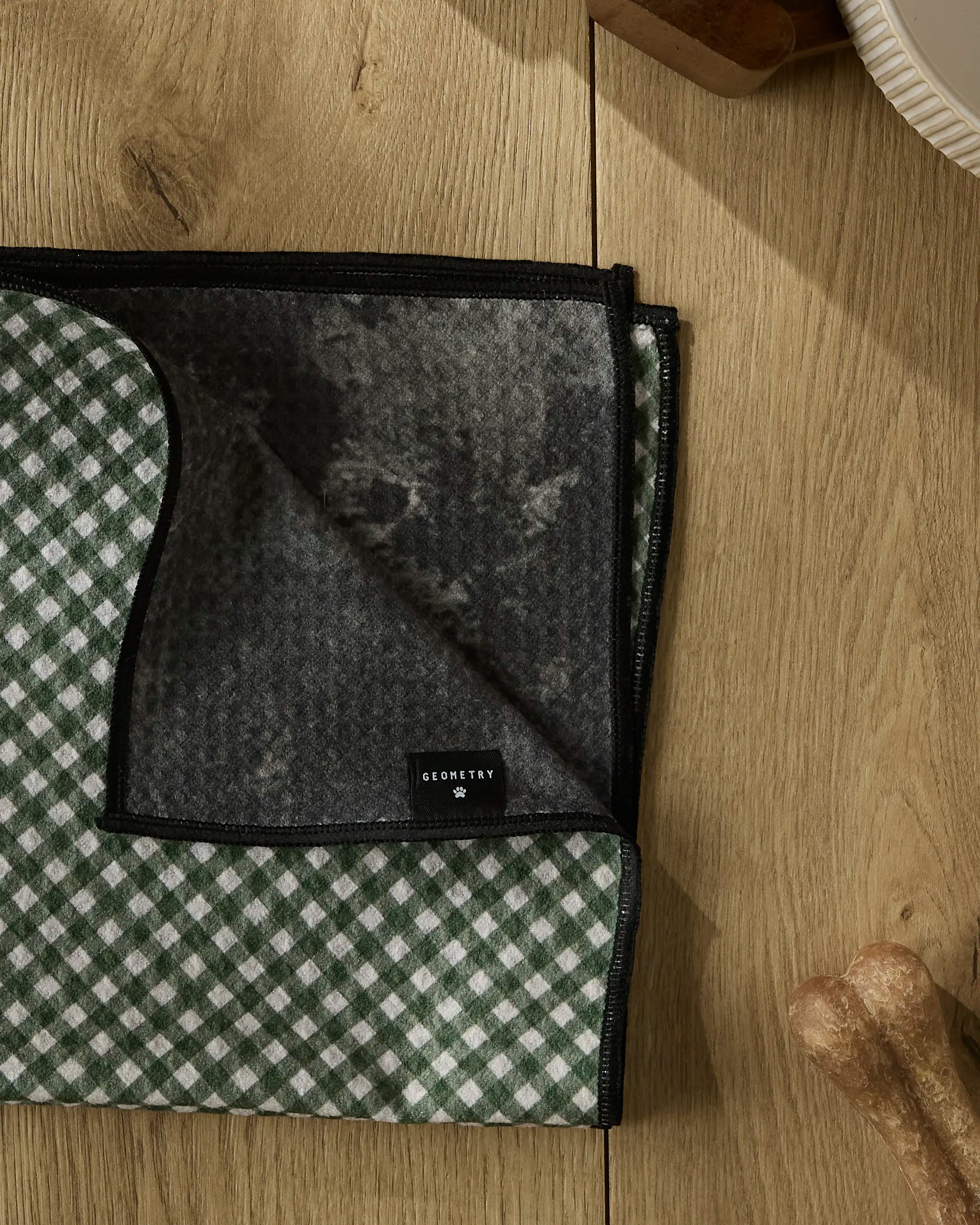 A Bramble Green dog toy sits next to a Geometry ultra-absorbent dog towel, ideal for quick clean-ups after playtime.