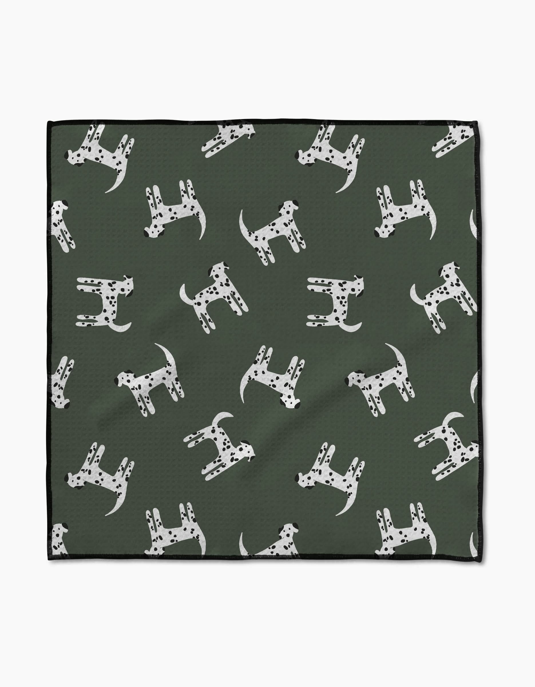 The Coit Creative “Dalmation Dogs” Paw Towel features a green Geoweave fabric with white Dalmatian dog patterns, each with unique black spots, and a chic black border for style and absorbency.