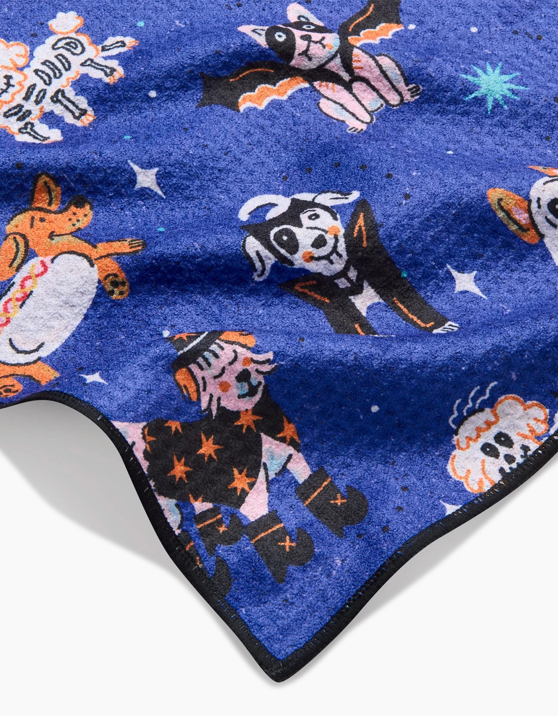 The Halloween Hounds by Camila Leão is a blue recycled pet towel featuring dogs in Halloween costumes—skeletons, bats, and pumpkins—among stars. Ultra-absorbent, its finished with a black border for a festive touch.