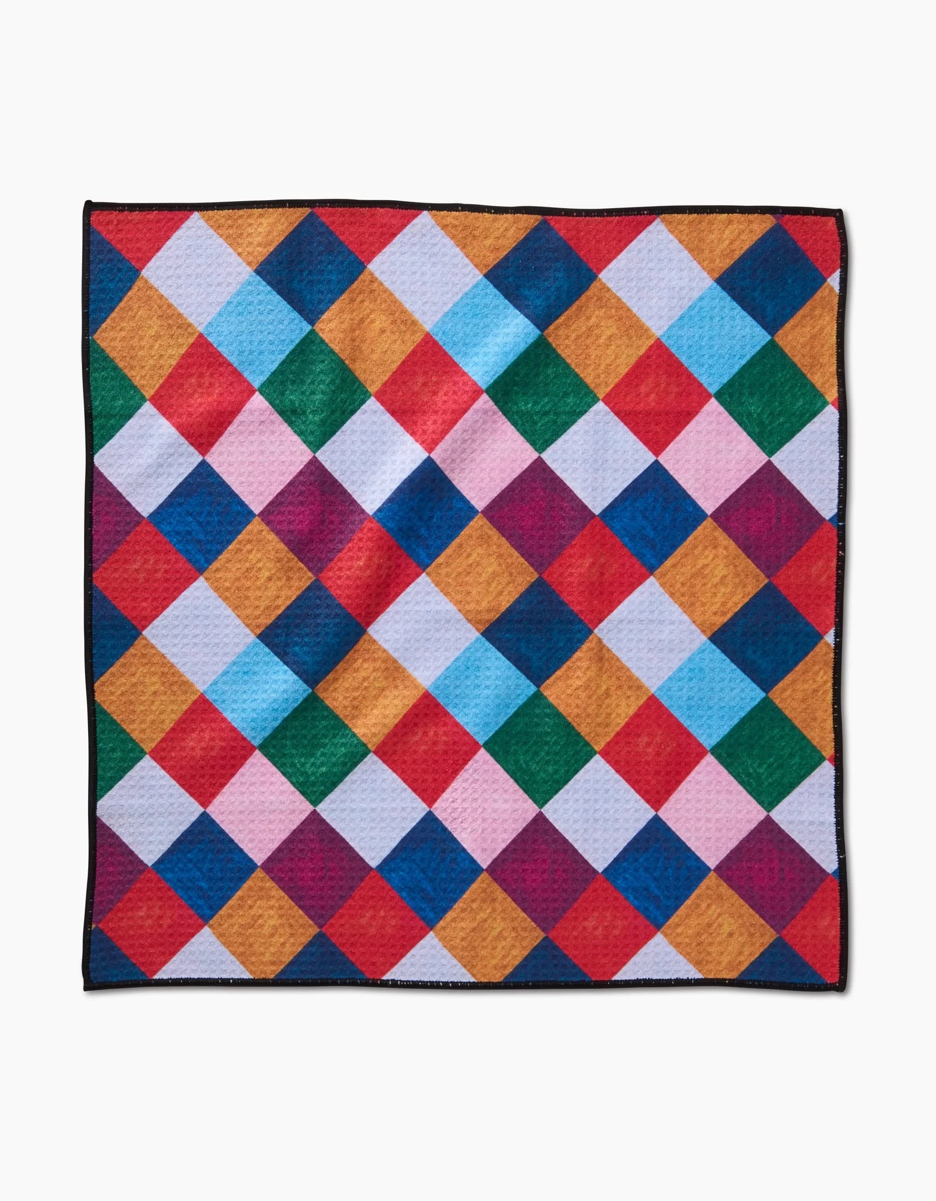 The Holiday Harlequin by Daria Solak is a colorful quilt with a diamond pattern in red, blue, yellow, green, pink, orange, and white squares—ultra-absorbent like a dog towel—with a slim black border on white.