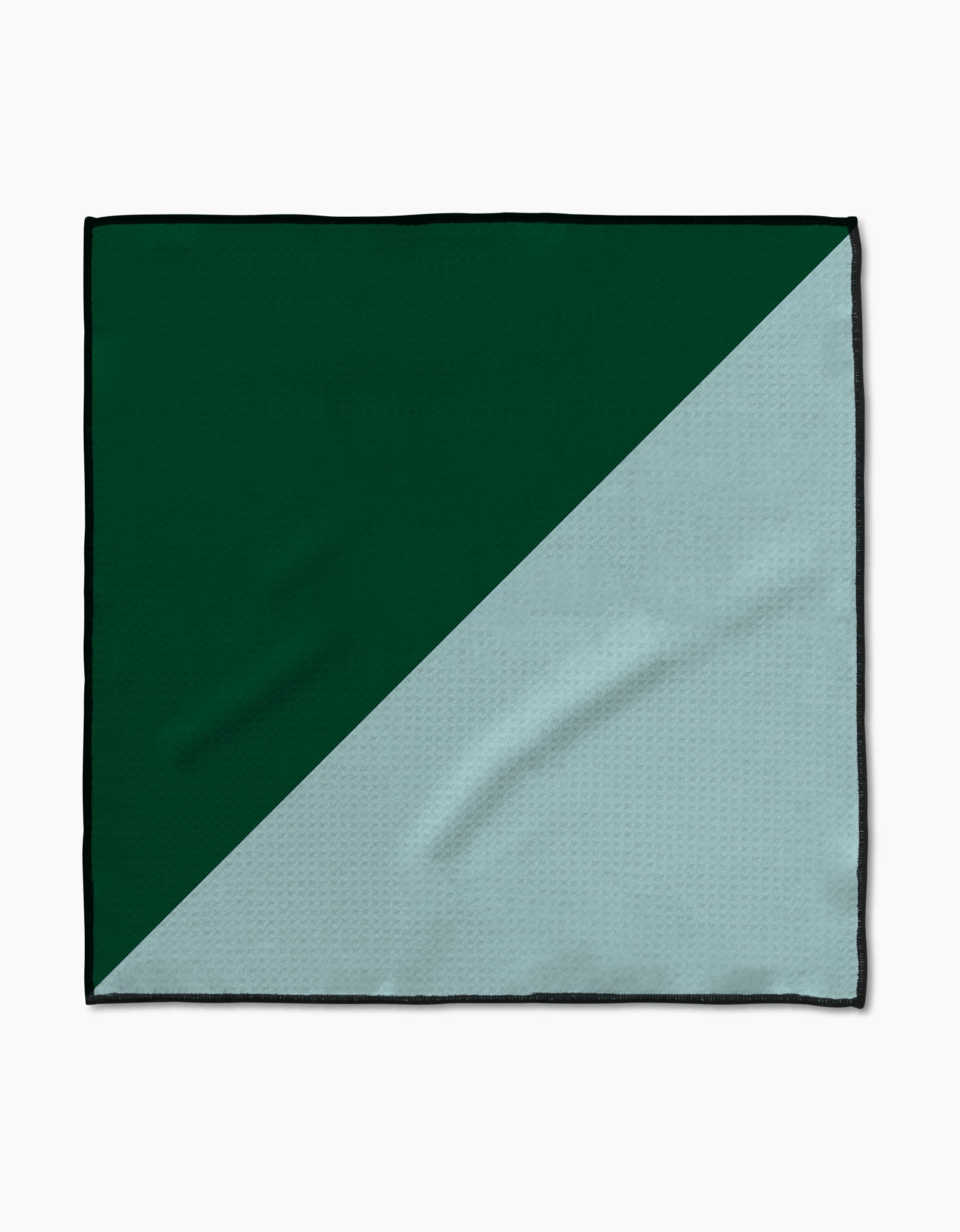 The Minted Oasis Paw Towel by Geometry features a rectangular shape with a diagonal split—dark green on the top left and light gray on the bottom right. Crafted from Geoweave™ fabric, it has a soft, subtly textured surface with visible creases.