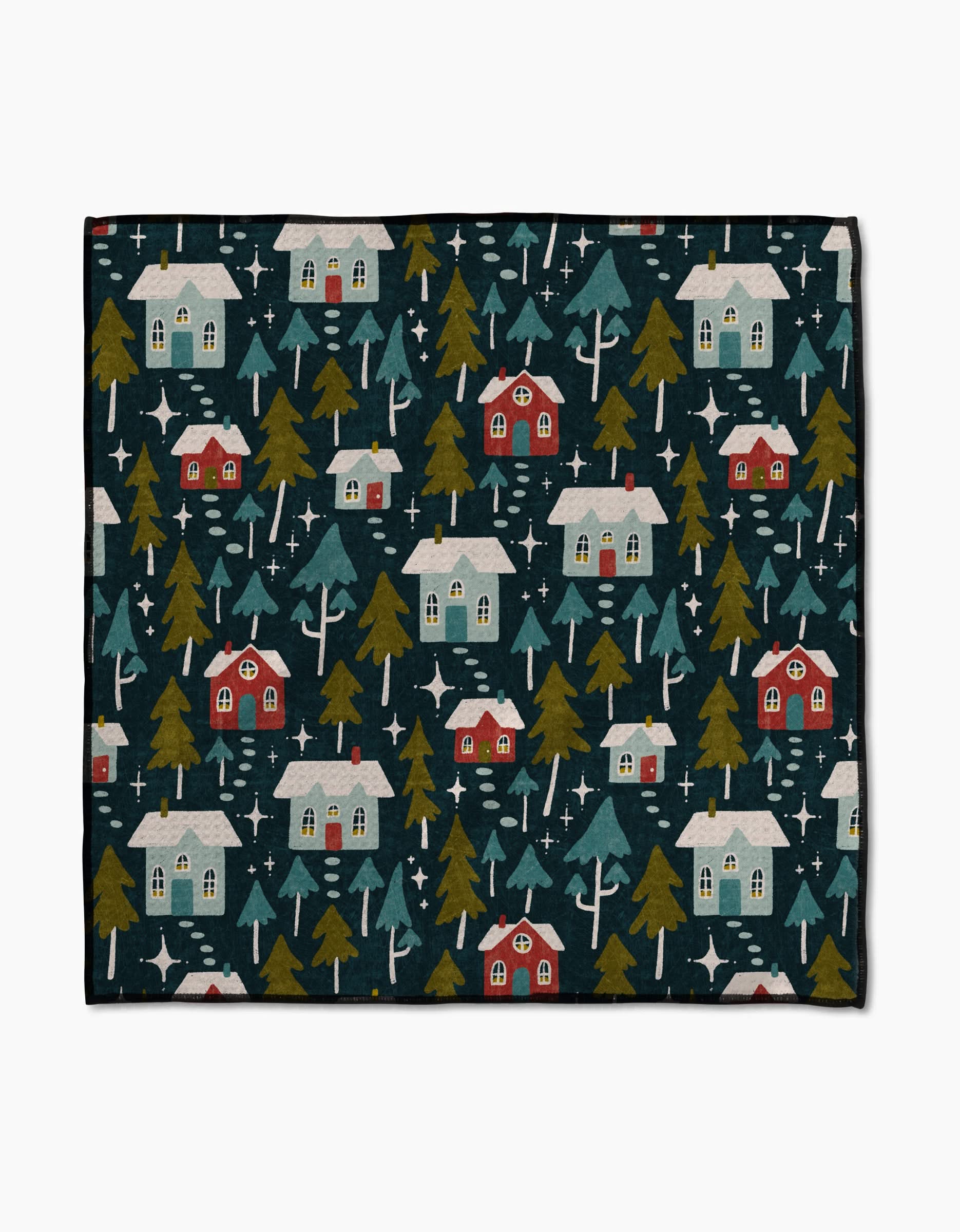 The Nico Dark blanket by Amy MacCready features a winter village scene with red and white houses, green trees, and white stars on dark blue Geoweave fabric—ultra-absorbent and cozy for chilly days.
