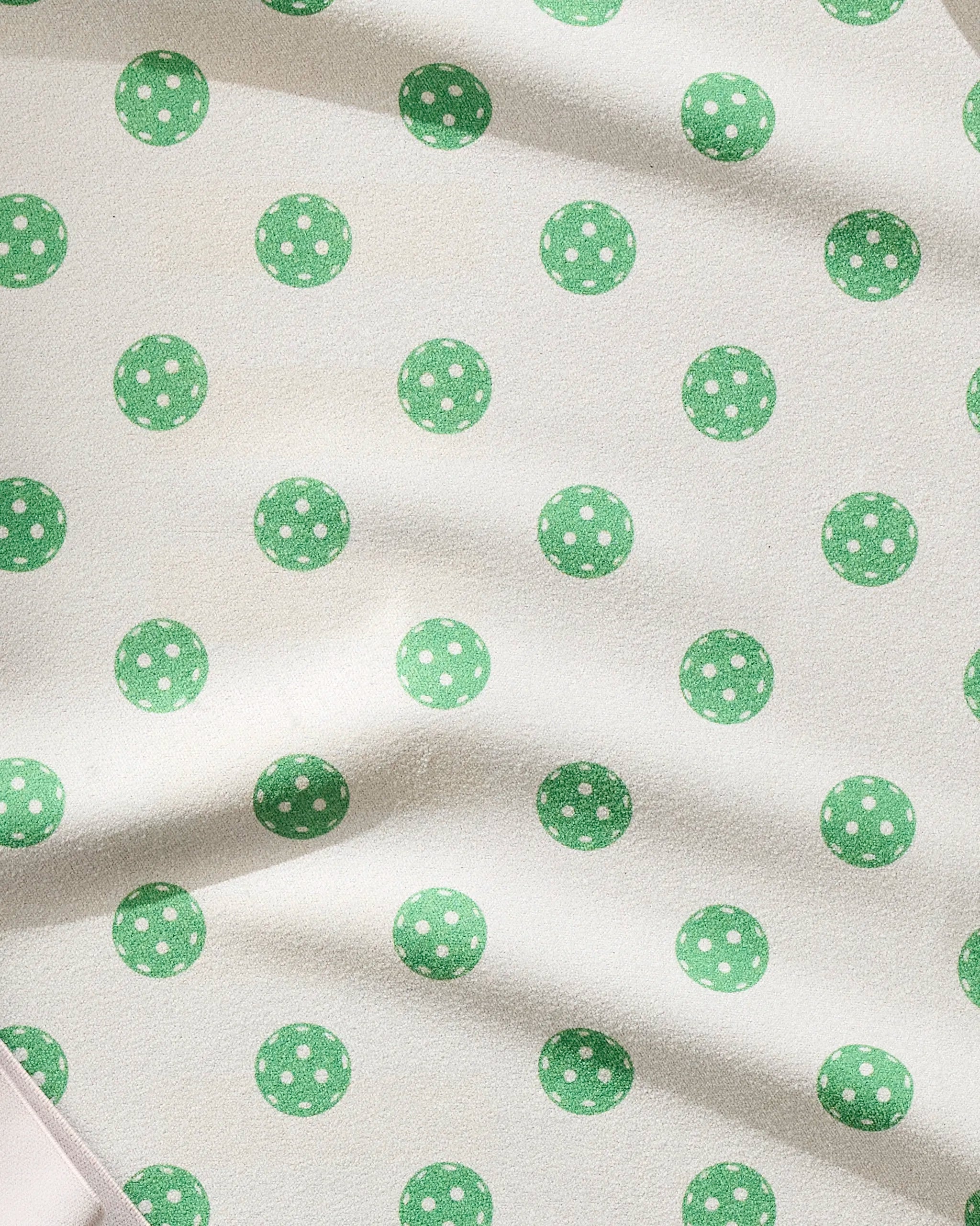 The Geometry Ace towel features a cream base with ultra-absorbent, fast-drying fabric and green polka dots accented by subtle white spots. Soft folds and shadows emphasize its textured look—ideal for workouts or fitness routines.