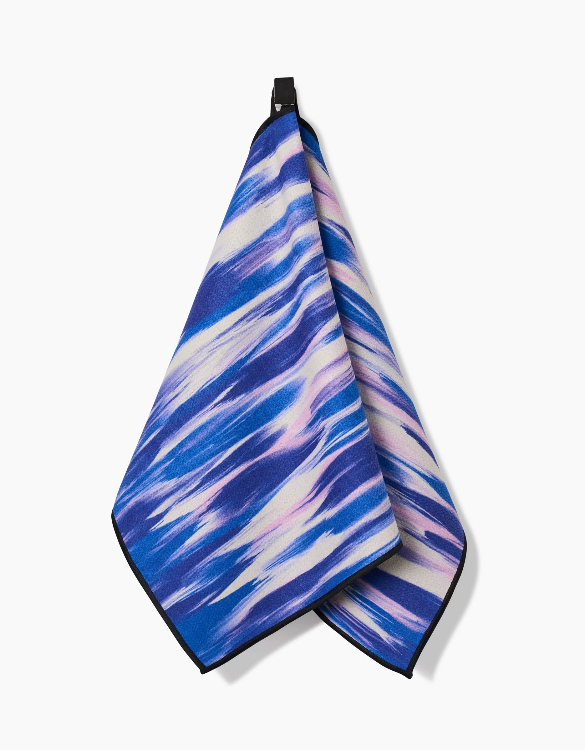 The GEOMETRY Blue Blast fitness towel features a blue, white, and purple abstract wave pattern. Made from ultra-absorbent recycled materials, it hangs from a black loop against a plain white background.
