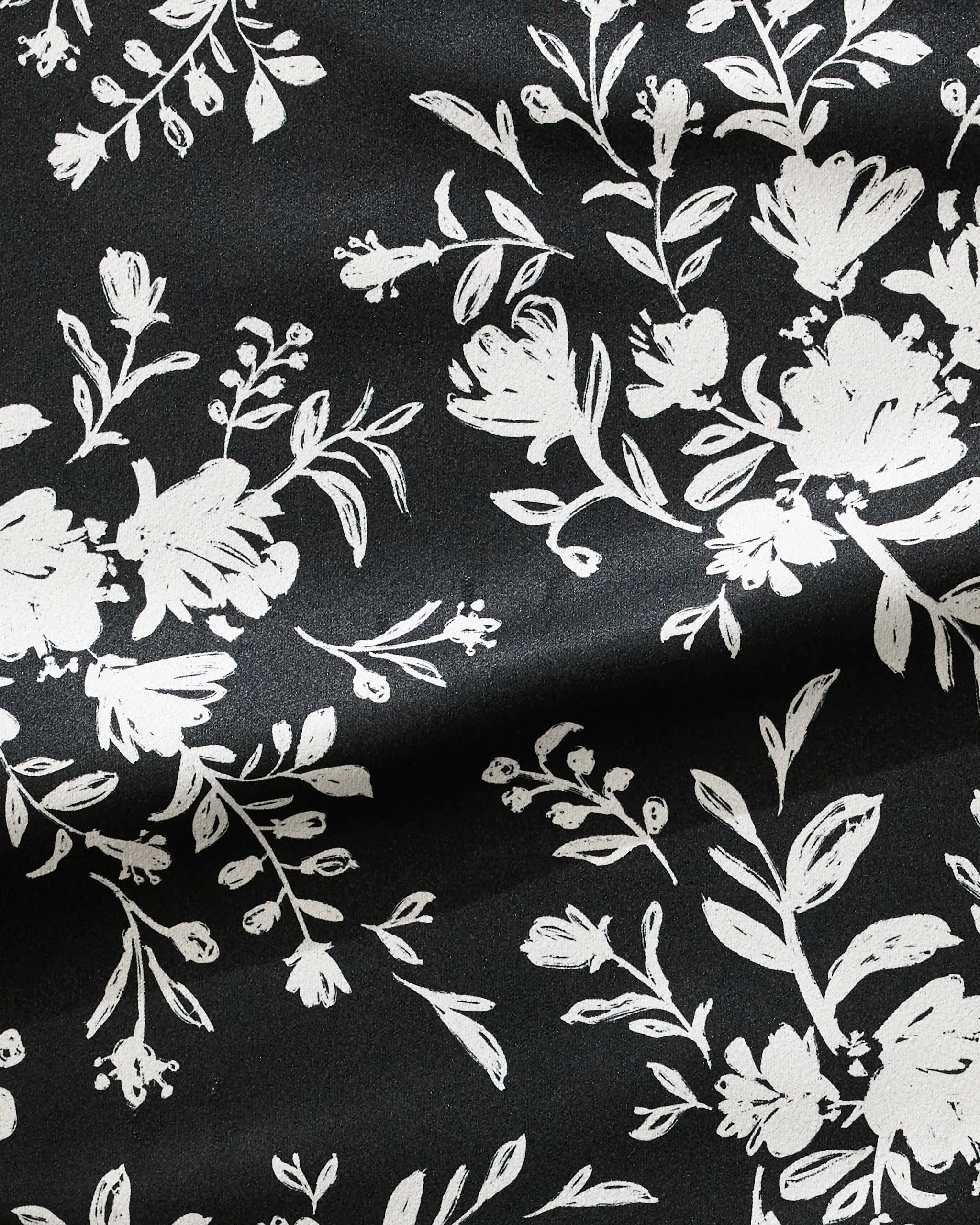 Botanical Silhouettes Charcoal by Danelys Sidron features black fabric with white floral patterns of flowers and leaves. This ultra-absorbent, slightly creased material is ideal as a quick drying fitness towel.