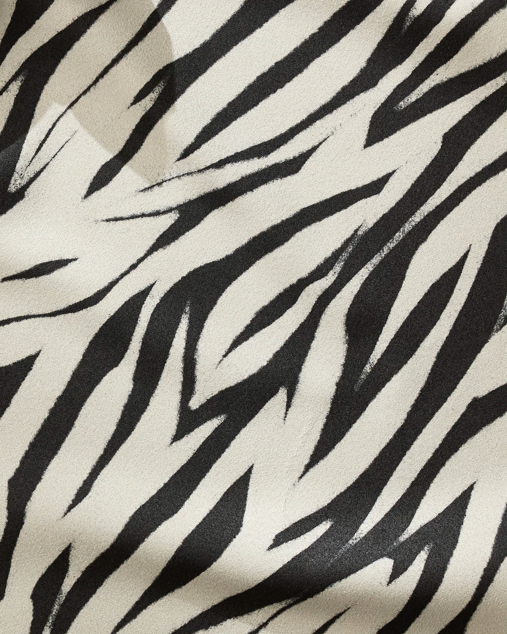 A close-up of Chase by GEOMETRY shows bold, irregular black and white zebra stripes on a smooth, slightly textured surface—crafted from recycled materials.