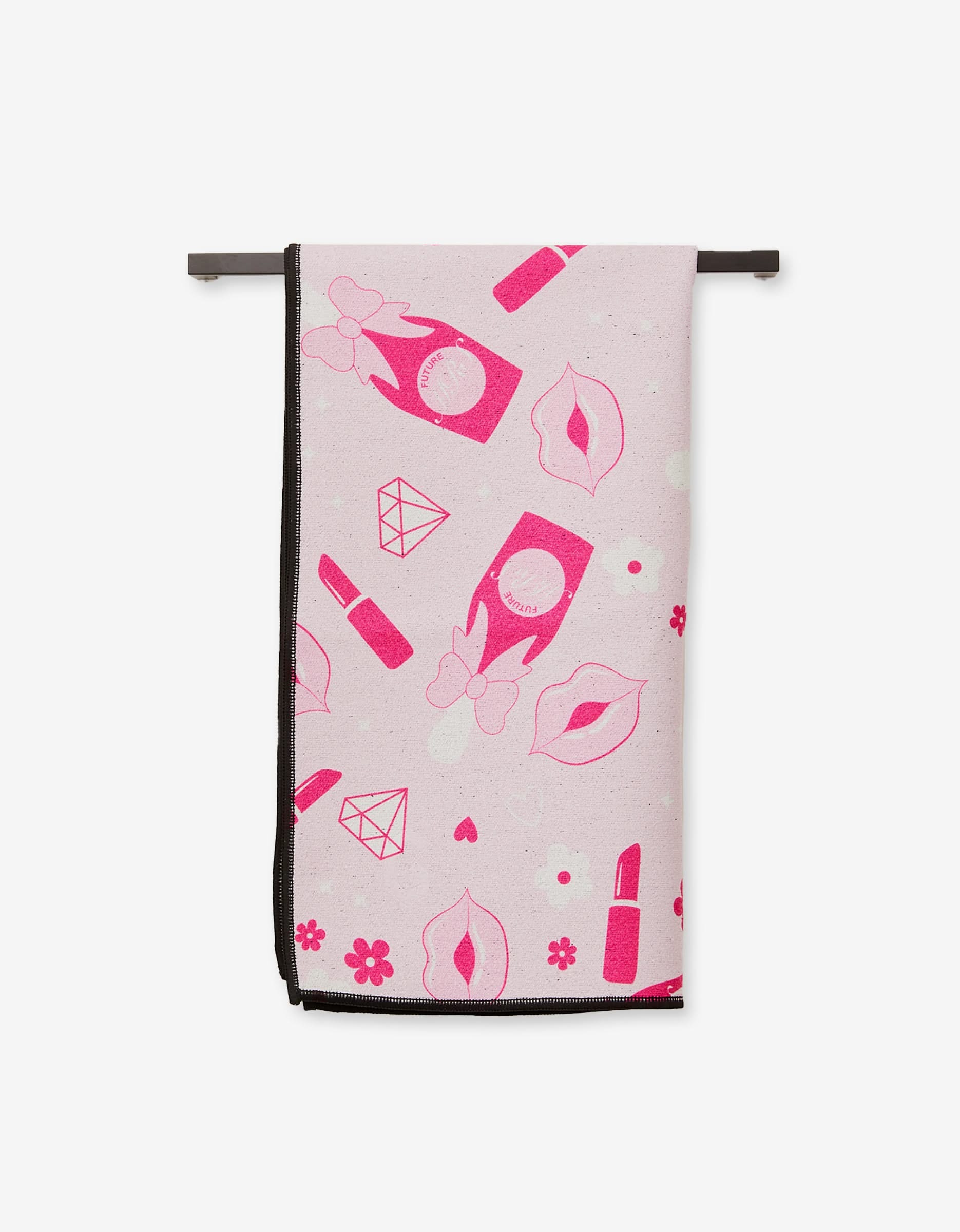 The GEOMETRY Cheers towel is an ultra-absorbent, pink fitness towel made from recycled materials with prints of lips, diamonds, flowers, lipstick, nail polish, and feminine symbols. It hangs on a black rack against a white background.