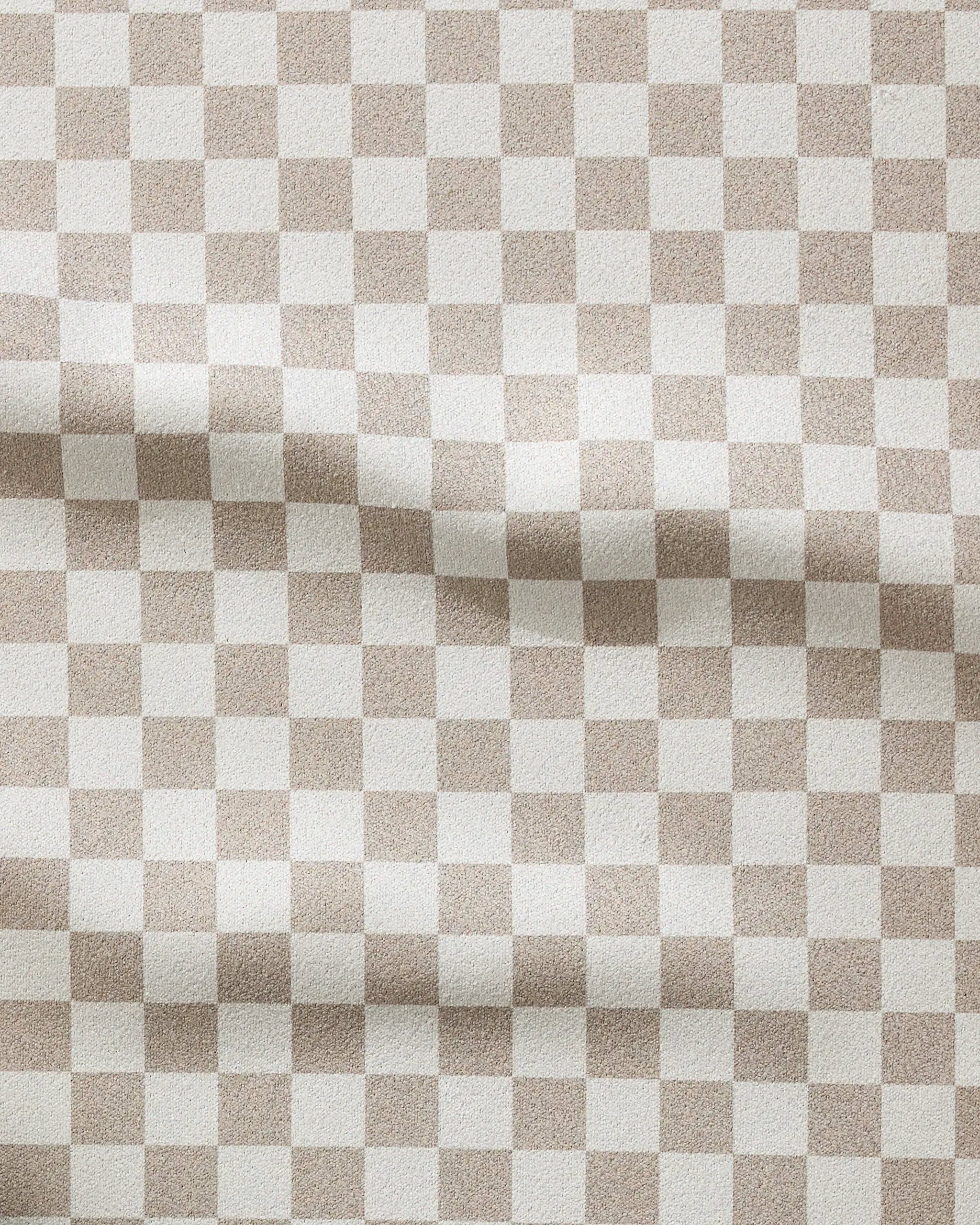 The GEOMETRY Chic Checker fitness towel features a wavy beige and white checkerboard pattern, offering a subtle textured look. Made from recycled materials, this ultra-absorbent towel is both stylish and eco-friendly.