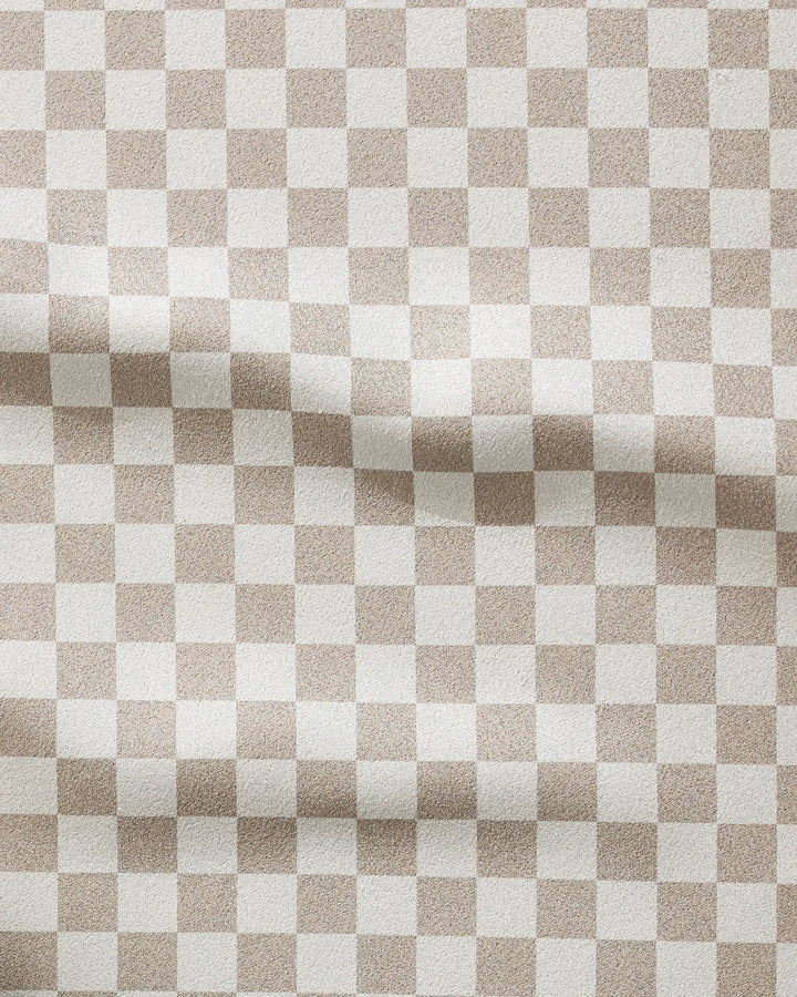 The GEOMETRY Chic Checker fitness towel features a wavy beige and white checkerboard pattern, offering a subtle textured look. Made from recycled materials, this ultra-absorbent towel is both stylish and eco-friendly.
