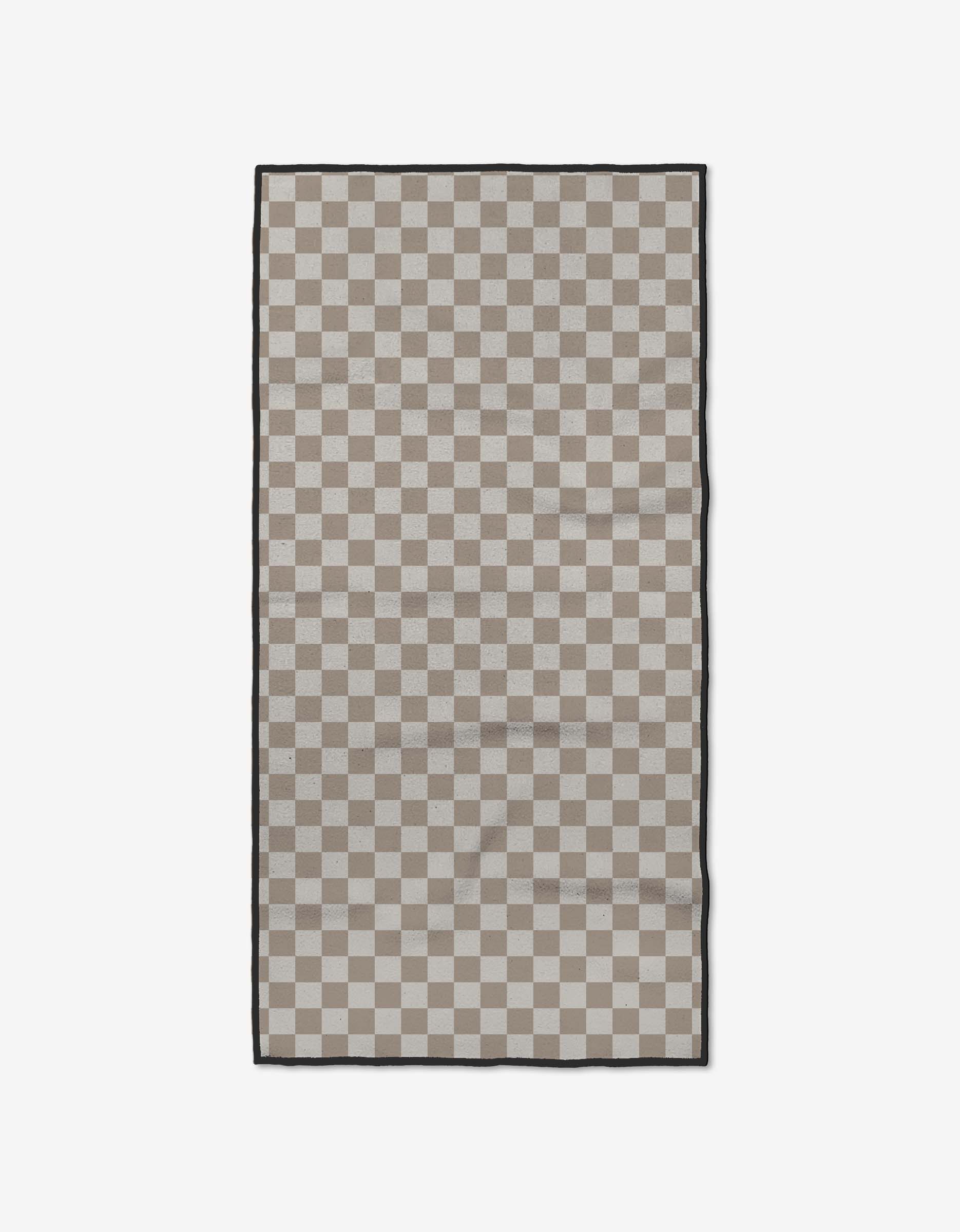 The GEOMETRY Chic Checker is a rectangular fitness towel featuring a beige and light gray checkerboard design with a slim black border, made from soft Geoweave fabric, shown on a plain white background.