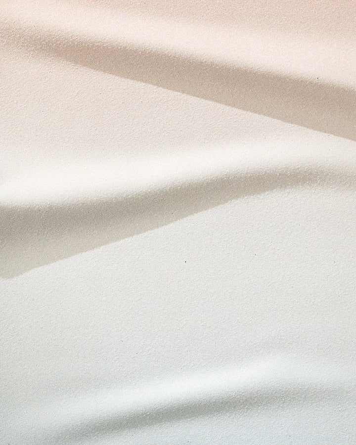 Close-up of the GEOMETRY Core towel in soft white, beige, and light grey tones with striped folds—ultra-absorbent and crafted from recycled materials.