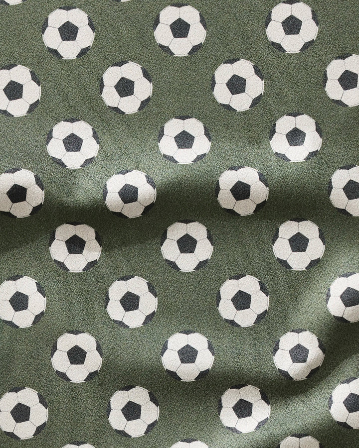 The Geometry Dribble is a green, ultra-absorbent fitness towel with a black-and-white soccer ball pattern and textured folds for quick drying.