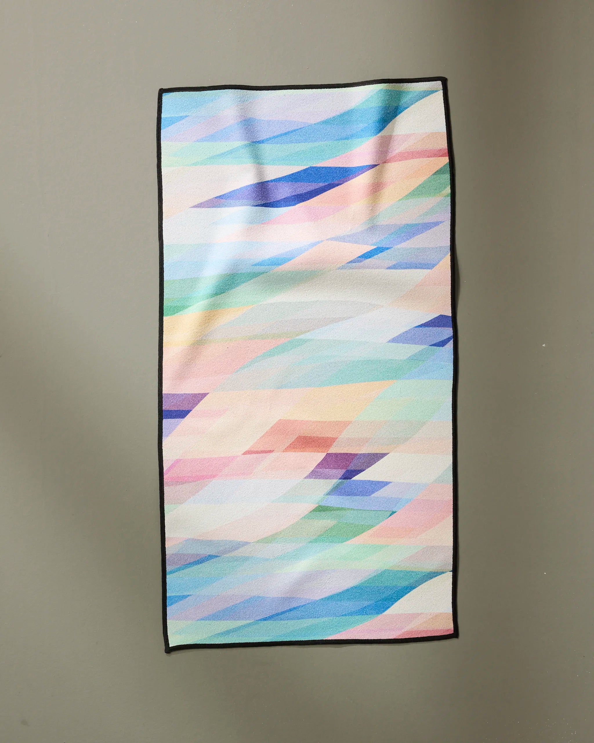 The Eventide rug by Rachel Parker is a rectangular, ultra-absorbent piece featuring overlapping pastel geometric shapes in blue, pink, green, purple, and yellow with a thin black border, displayed against a plain background.