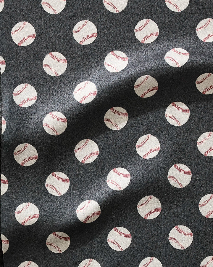 A close-up of the Geometry Fastball fitness towel shows ultra-absorbent fabric with a repeating white baseball pattern on dark background. Waves in the towel highlight its fast-drying properties and soft texture.