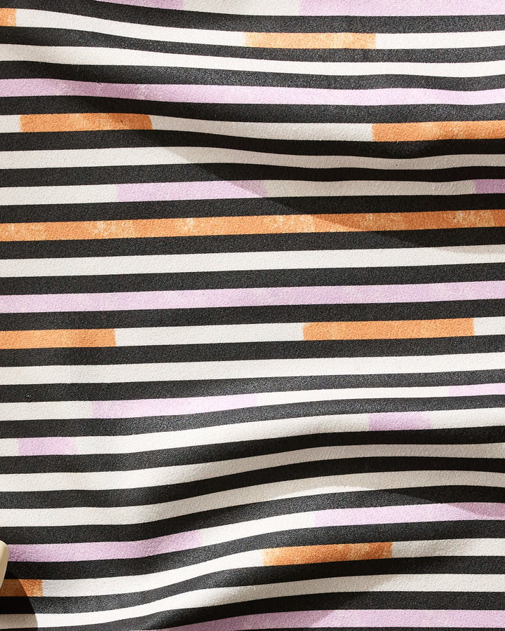Geometry’s "Funk On" fabric features irregular horizontal stripes in black, white, orange, and purple. Made from recycled materials, it has a slightly wrinkled appearance with dynamic color interspersed among the monochrome lines.