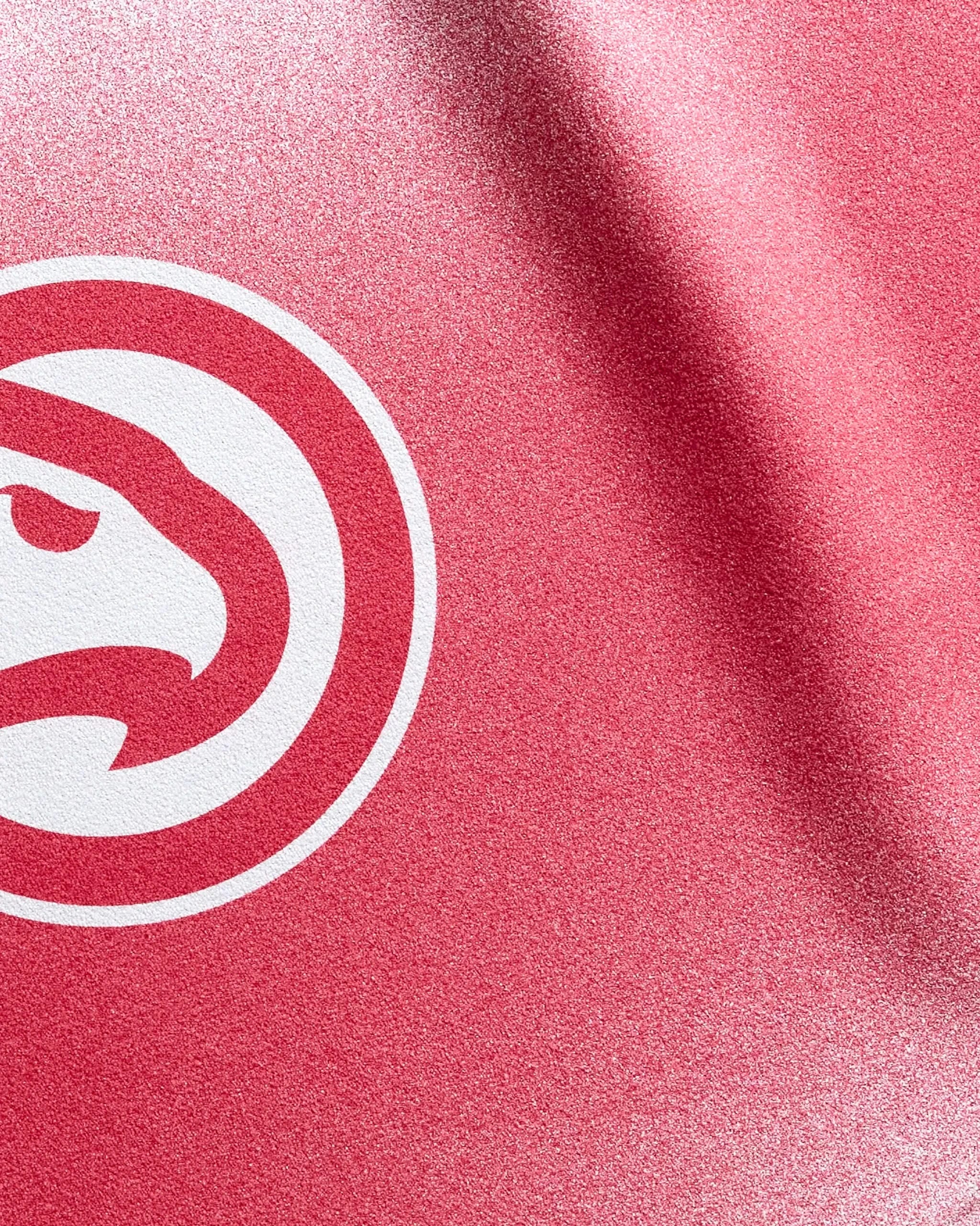 Close-up of the Hawks Fade fitness towel by NBALAB x Geometry, featuring red textured fabric and a white circular logo with a stylized hawk’s head, representing the Atlanta Hawks.