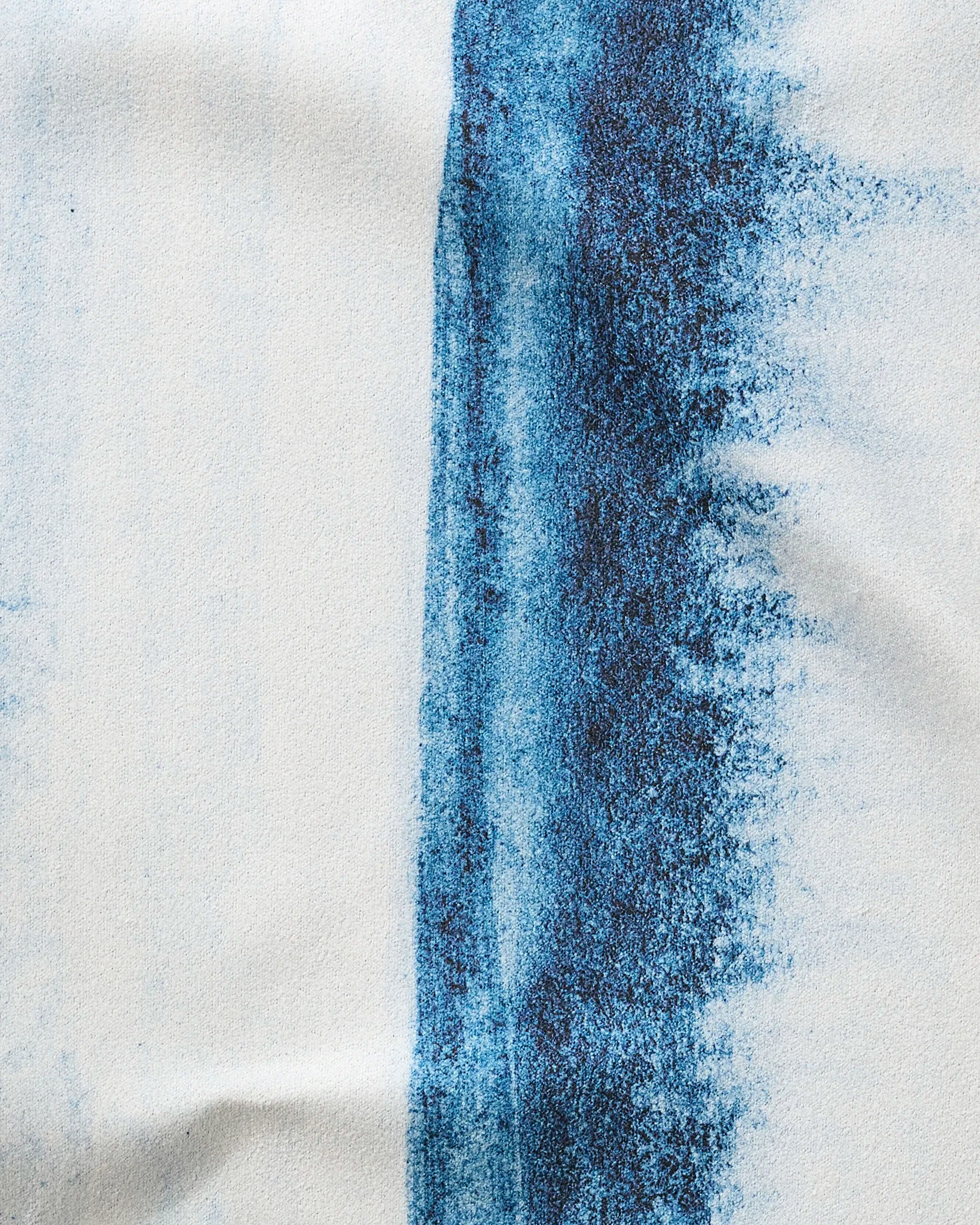 In The Distance" by GEOMETRY features a white textured surface with a bold vertical blue streak fading right, echoing the look of an ultra-absorbent towel with gradient hues, scattered specks, and irregular edges.