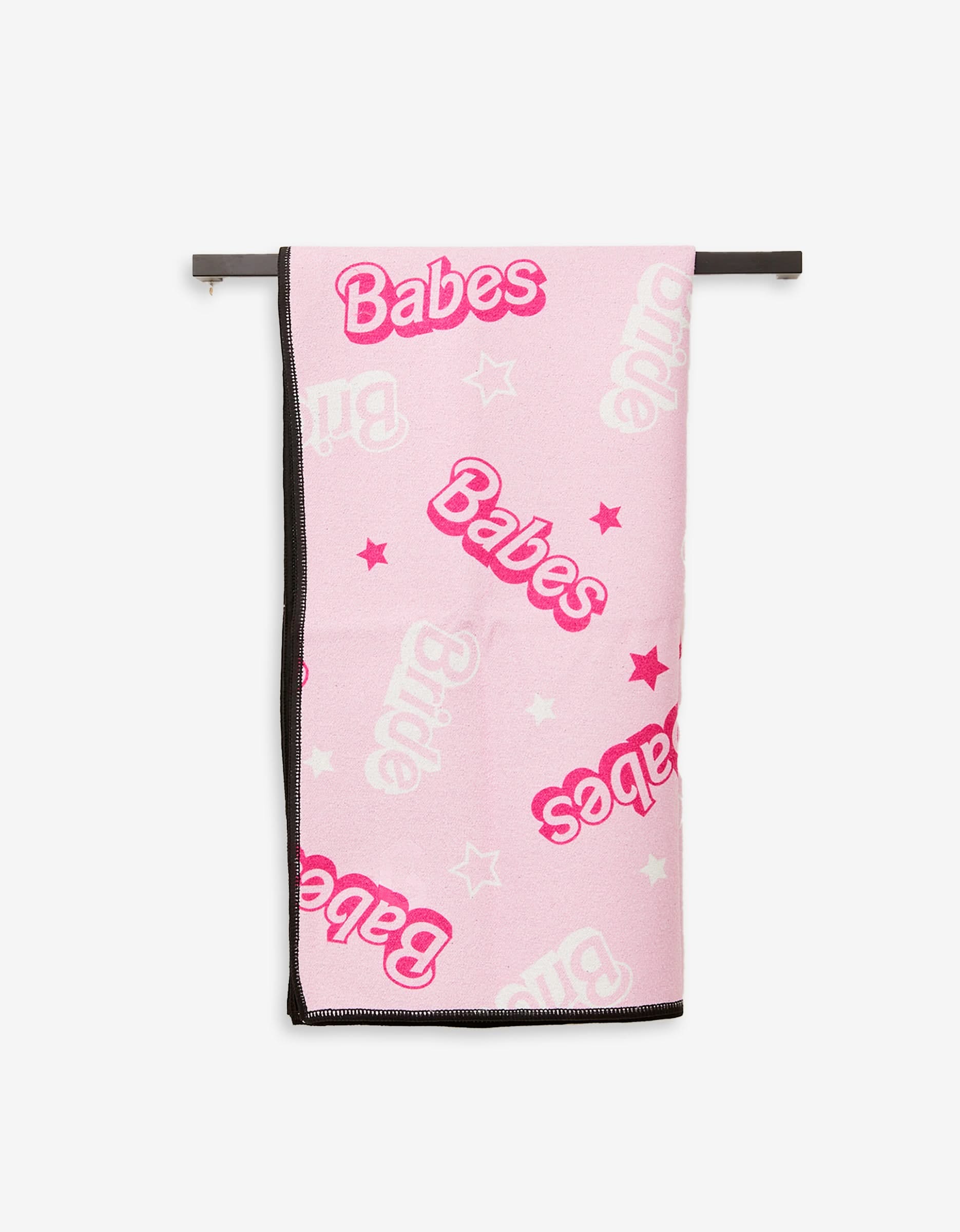 The GEOMETRY Lets Go Party Fitness Towel, made from ultra-absorbent recycled materials, is pink with white and pink stars and features “Babes” and “Bride” in bold letters, shown hanging on a black rod.