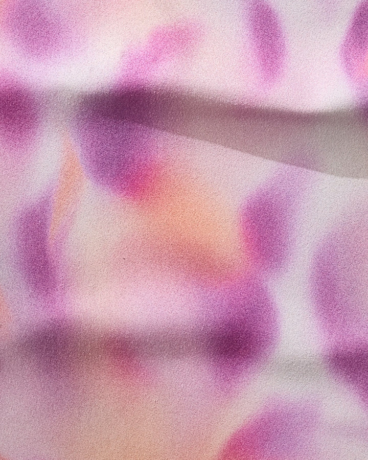 The GEOMETRY Magenta fitness towel is crafted from recycled materials, showcasing pink, purple, and orange watercolor-inspired blotches with subtle horizontal folds for a soft, dreamy look.