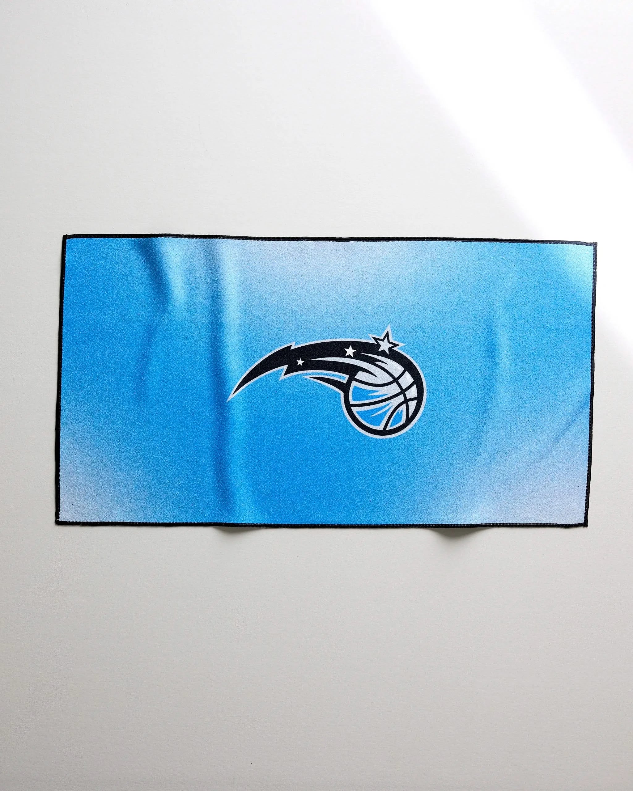 A rectangular blue Mavericks Fade fitness towel by NBALAB x Geometry features the Dallas Mavericks logo in the center, made from Geoweave fabric and shown on a plain white background.