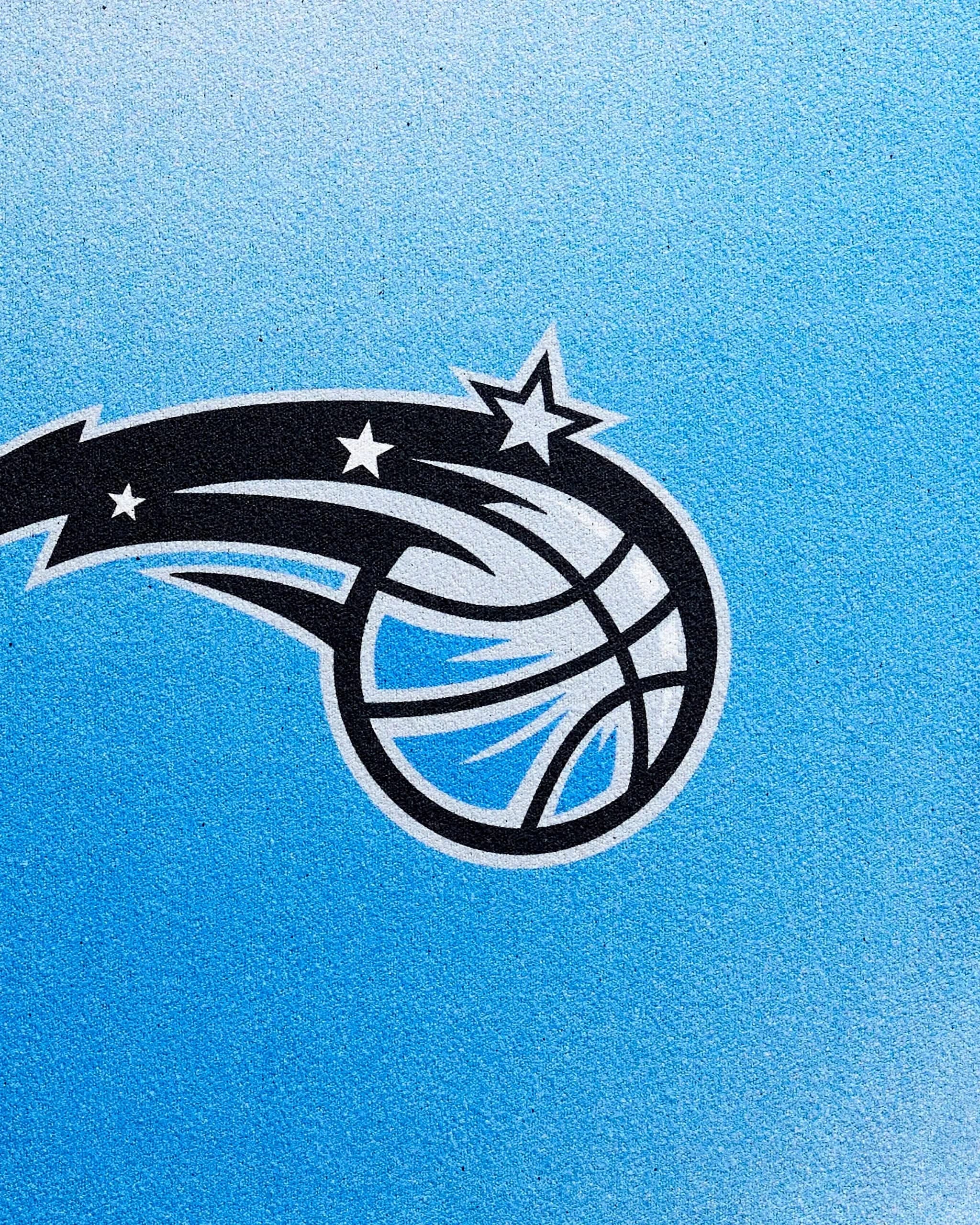 A stylized basketball with stars and motion lines, inspired by the Mavericks Fade logo, is featured on a textured blue background—an ideal look for the NBALAB x Geometry NBA fitness towel crafted from sustainable Geoweave fabric.