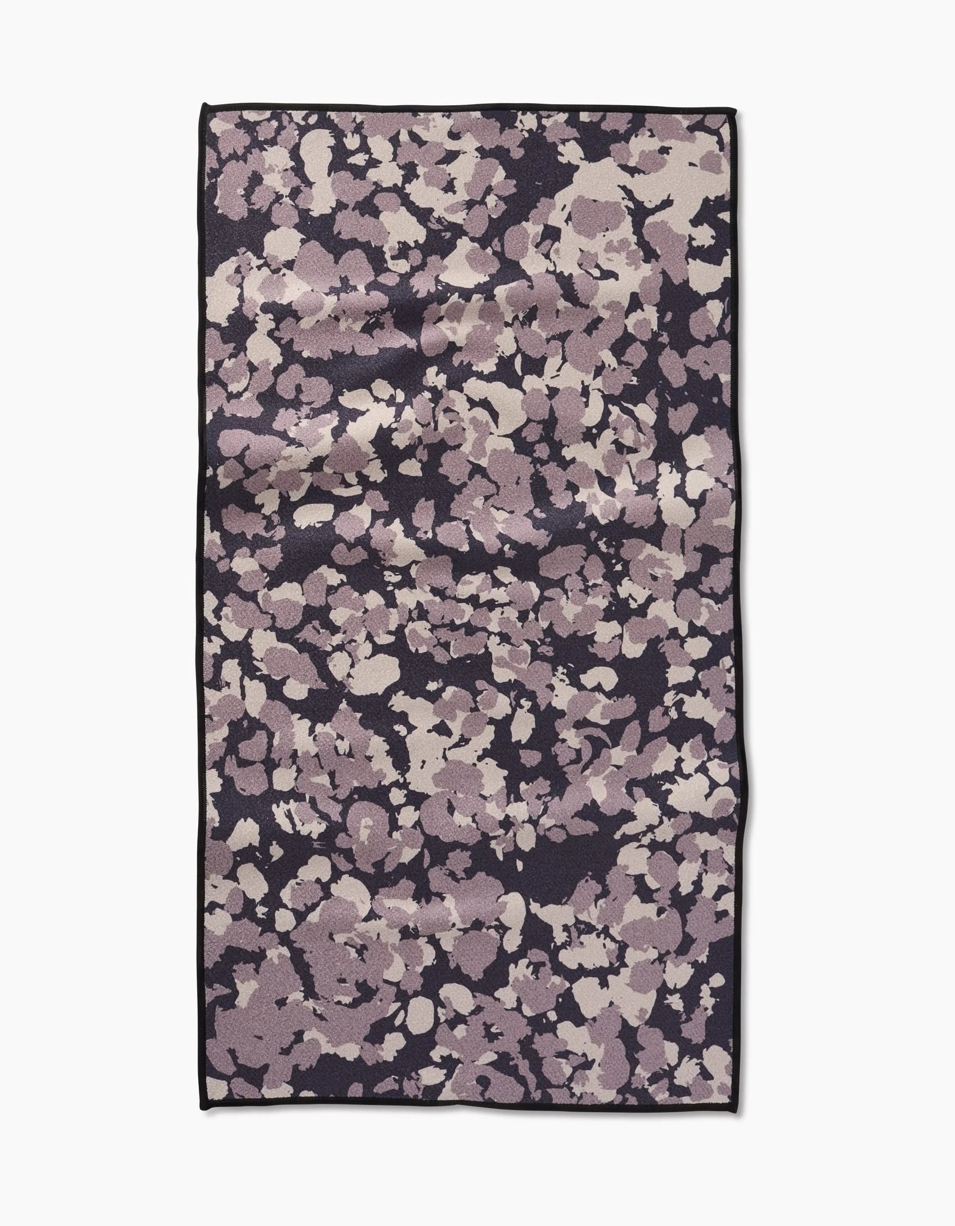 The GEOMETRY Metro Mesh is a rectangular fitness towel with an abstract lavender, mauve, and cream pattern on a dark background, bordered in black—crafted from ultra-absorbent recycled materials.