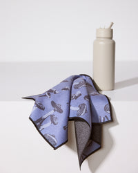 A gray water bottle with a straw sits on a white surface next to Geometry’s ultra-absorbent Moody Autumn Mushrooms fitness towel, draped in purple and adorned with a black mushroom pattern.