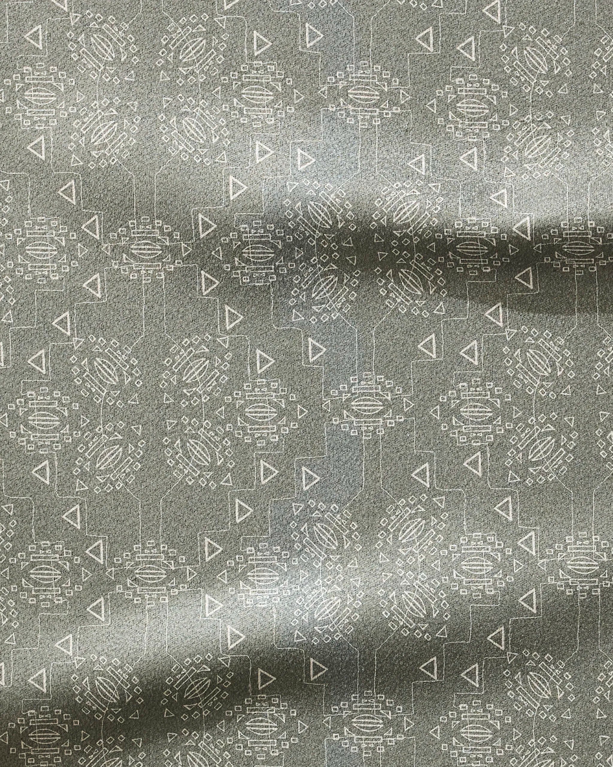 The Mountain Bloom fitness towel by Ash Cascade features gray fabric with a subtle sheen and a repeating pattern of white circles, triangles, and rectangles. Ultra-absorbent with gentle horizontal folds.