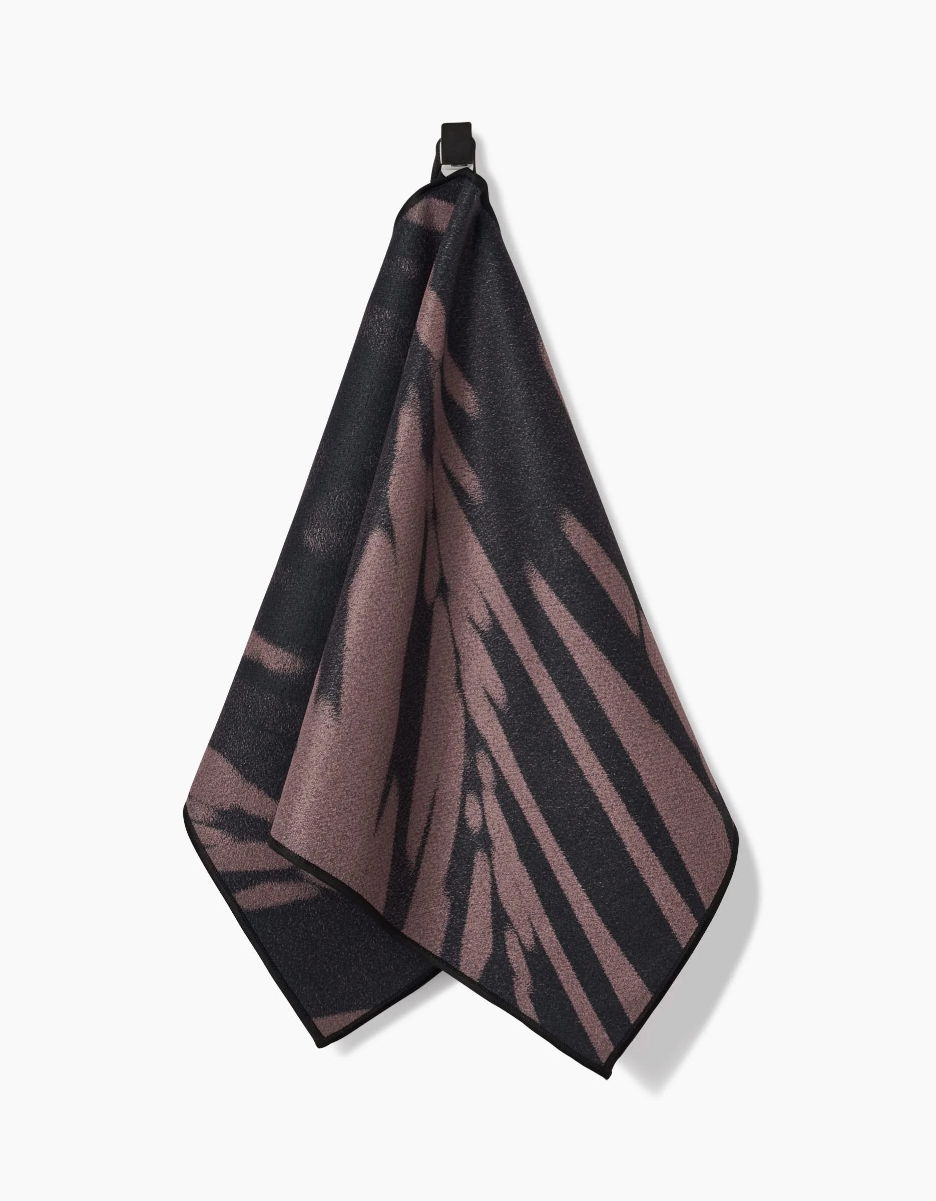 The GEOMETRY Palm Shadow is an ultra-absorbent fitness towel with a black and mauve abstract pattern, made from Geoweave fabric, and hangs by a black loop against a white background.
