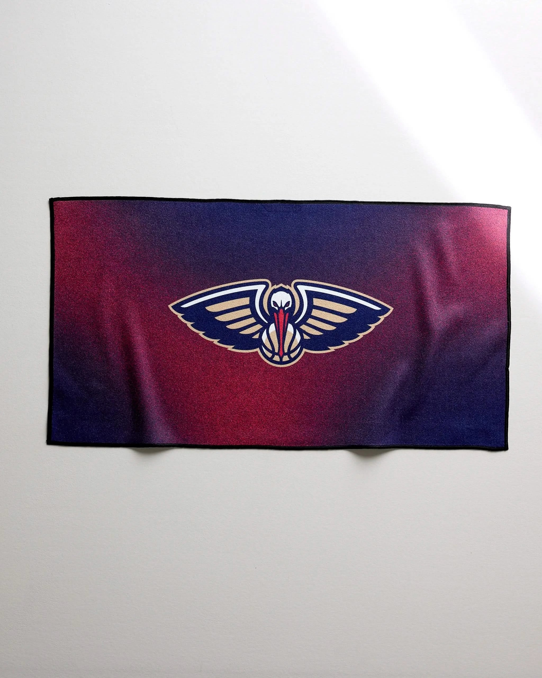 The NBALAB x Geometry Pelicans Fade is a rectangular, quick-drying gym towel with a red and blue gradient background and the New Orleans Pelicans logo at the center.