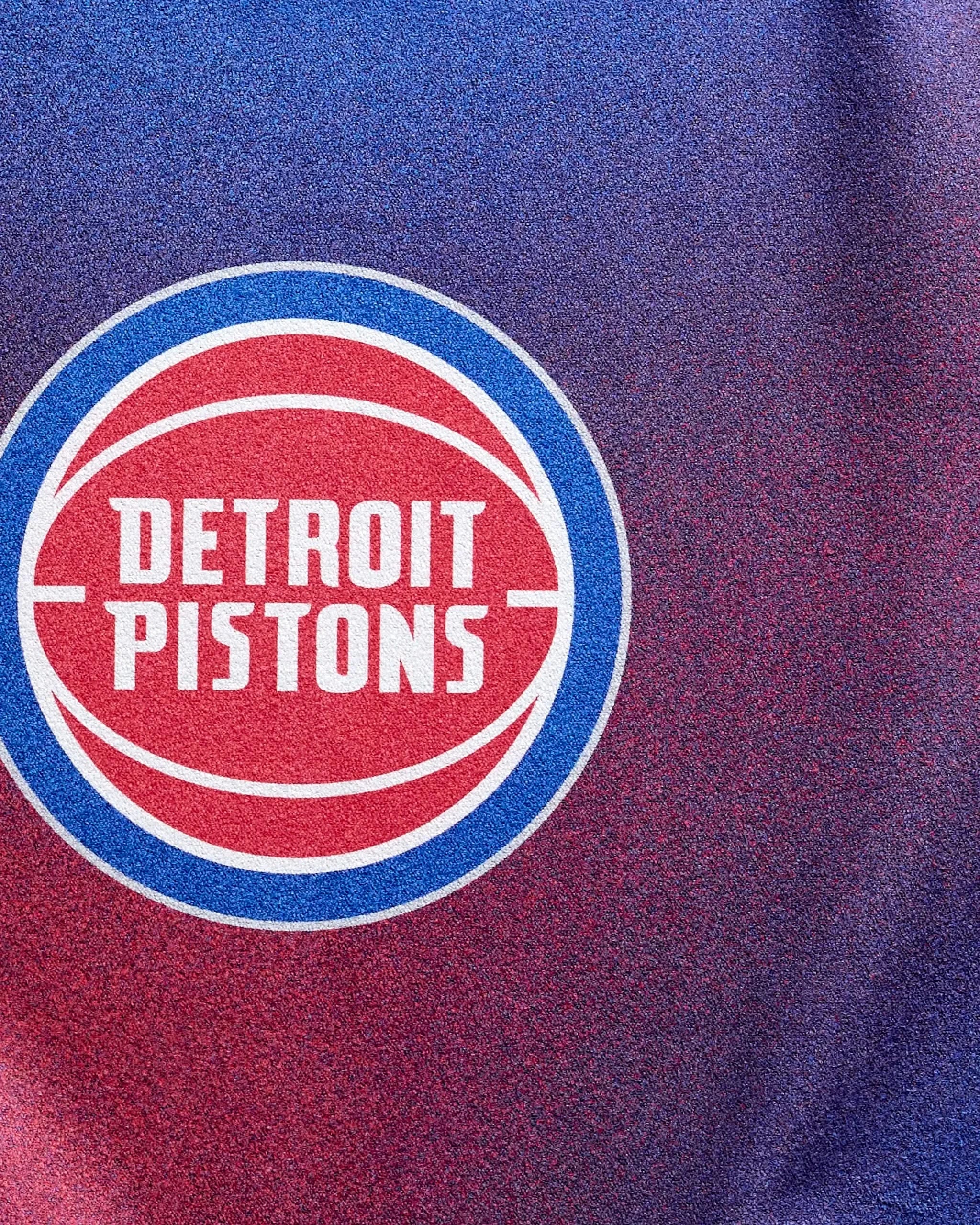 Close-up of the Pistons Fade by NBALAB x Geometry features the Detroit Pistons logo in white, red, and blue on a textured gradient from blue to red—ideal inspiration for your next NBA fitness or sustainable gym towel.