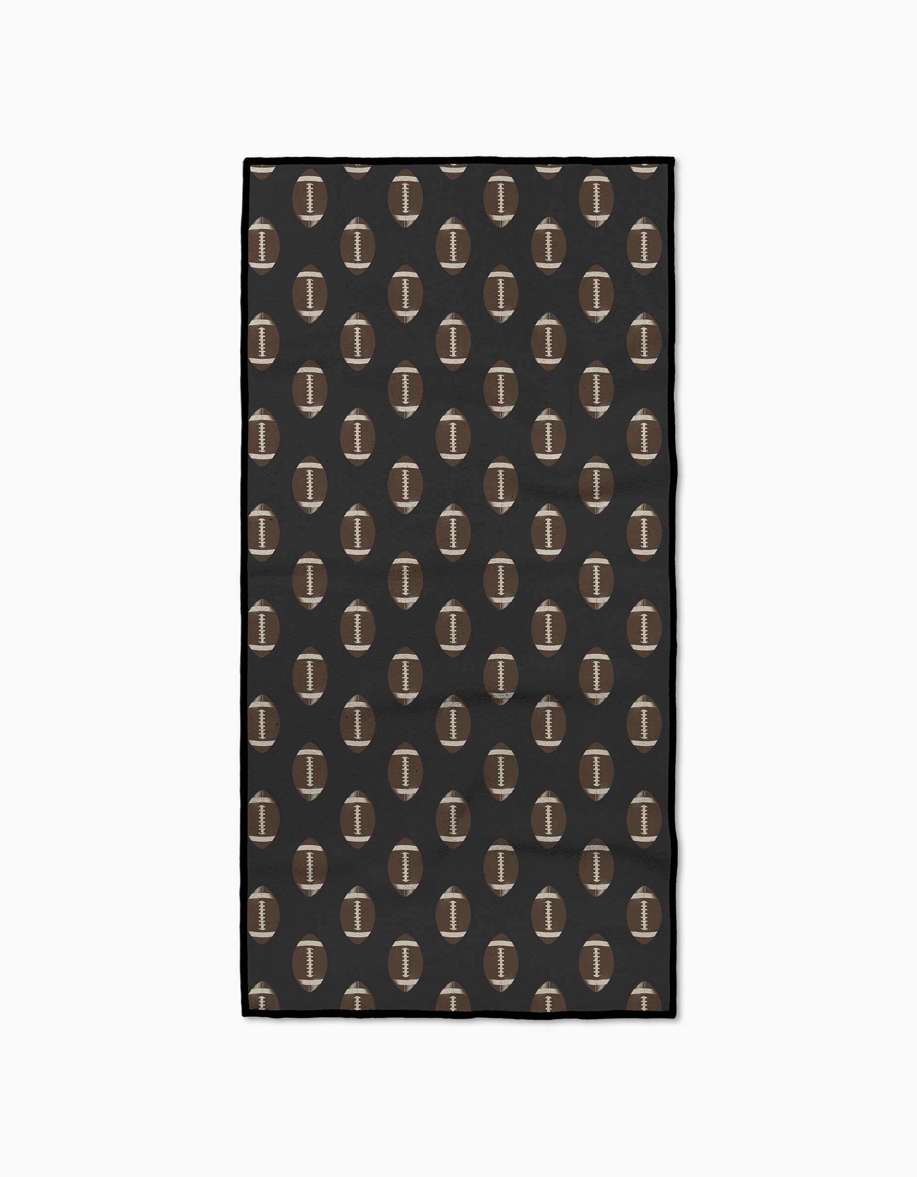 The Geometry Rush Fitness Towel features a rectangular shape and a repeating pattern of brown footballs with white stitching on a dark background, made from ultra-absorbent post-consumer recycled materials.