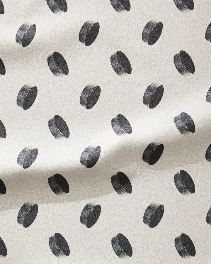 The Geometry Slapshot is a cream-colored, ultra-absorbent fitness towel made from recycled materials, featuring black 3D polka dots and a softly textured surface with gentle folds for style and function.