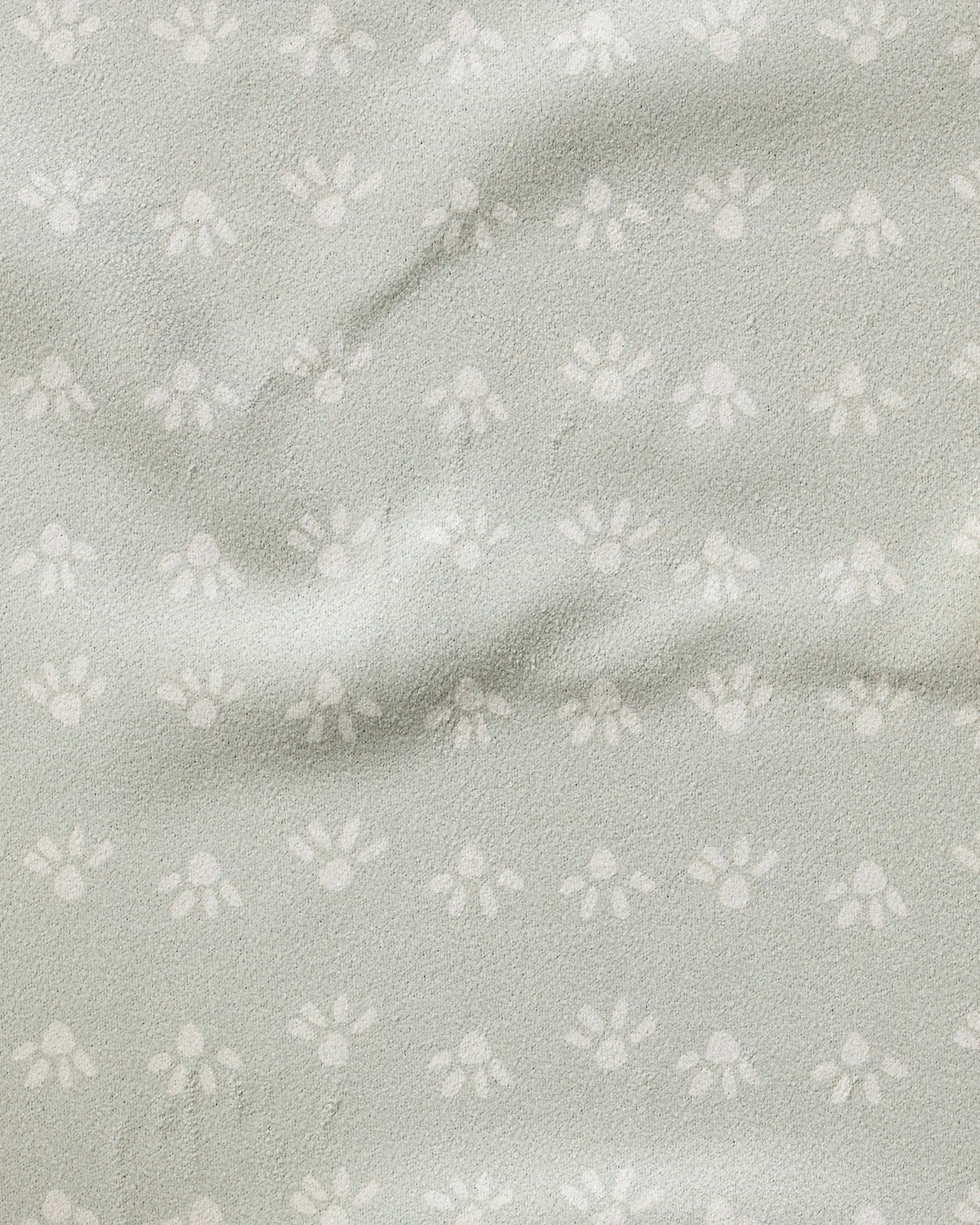 The Sun Bursts towel by Anee Shah is ultra-absorbent, light grey, and features a subtle small white paw print pattern with a slightly wrinkled, textured surface.