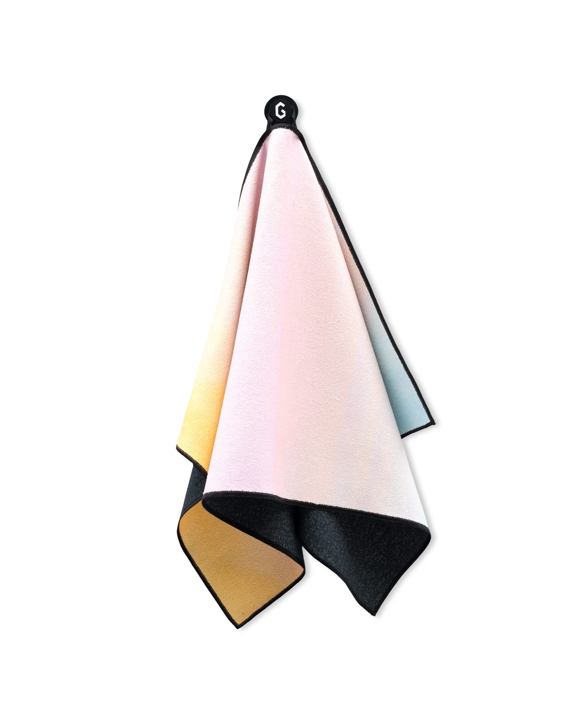 The GEOMETRY Magna - Sunrise towel features a pastel gradient in yellow, pink, and blue, made from ultra-absorbent microfiber with a black recycled-material backing. It hangs from a black loop labeled with a white G.