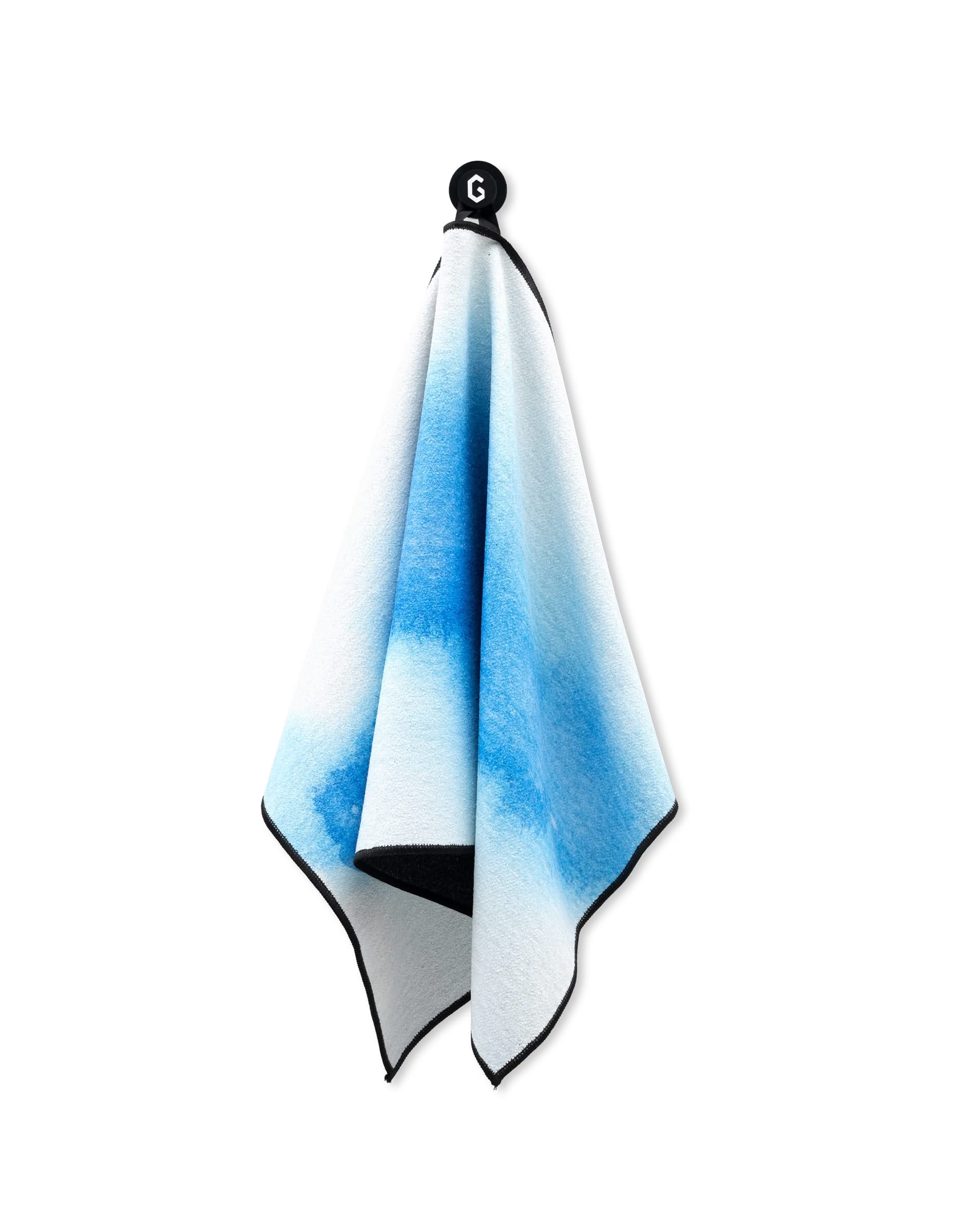 A Magna - The Soul towel by GEOMETRY with a blue gradient hangs from a black hook on a white background. Featuring black edging, this gym towel is ultra absorbent, soft, and ideal for any fitness routine.