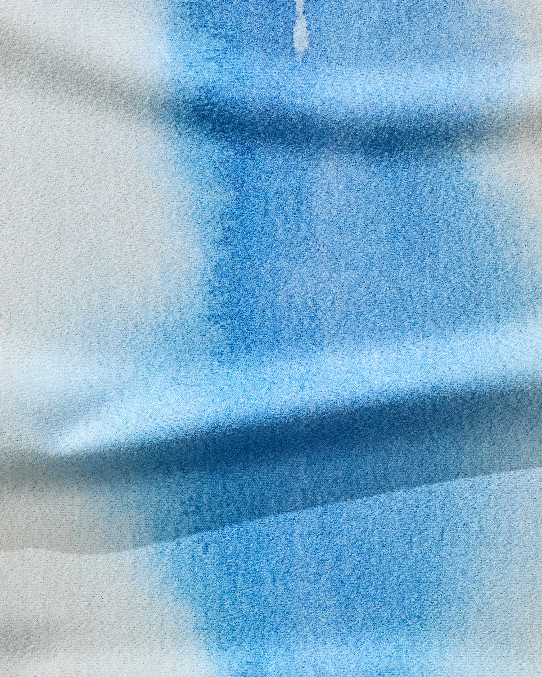 A close-up of blue watercolor softly blending on white paper, evoking the gentle absorption of The Soul recycled gym towel by GEOMETRY.