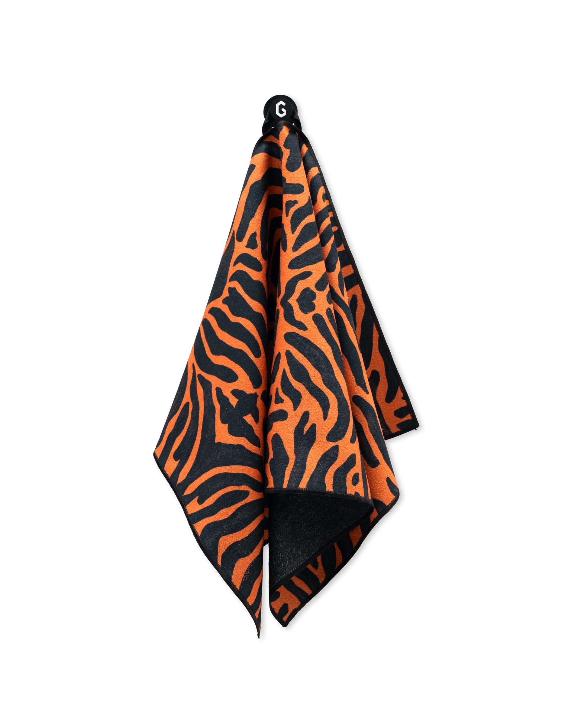 A GEOMETRY Magna - Tiger fitness towel, featuring an orange and black tiger stripe pattern and made from recycled materials, hangs from a hook against a white background.