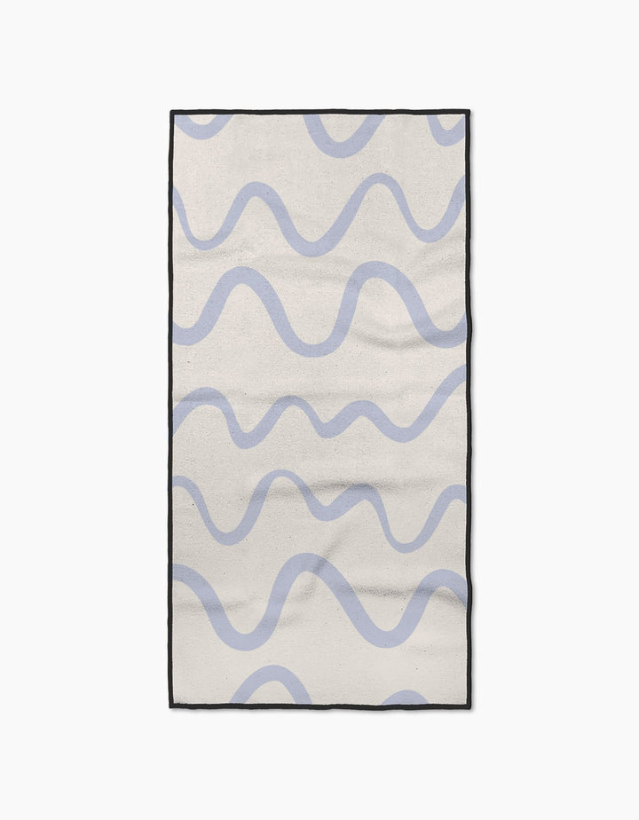 The Wavy Stripe in Blue rug by Teri the Butter features a cream base with light blue wavy stripes, a black border, and a simple, modern look. Made from ultra-absorbent materials for quick drying after spills or cleaning.