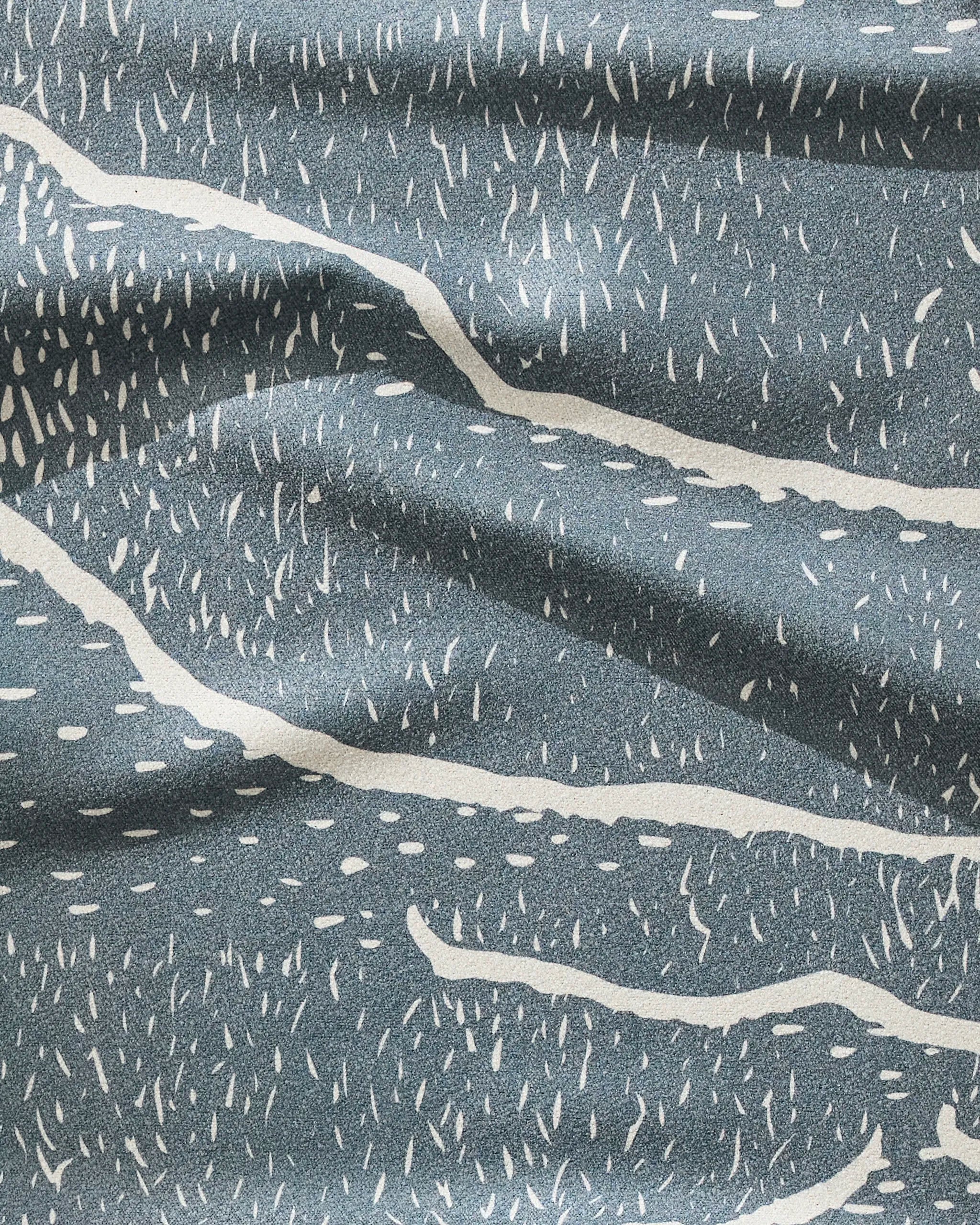 A close-up of GEOMETRY’s Wetlands Midnight towel shows blue fabric with white, wavy, abstract lines and dotted patterns. The ultra-absorbent, soft folds make it perfect for staying dry during your workout.