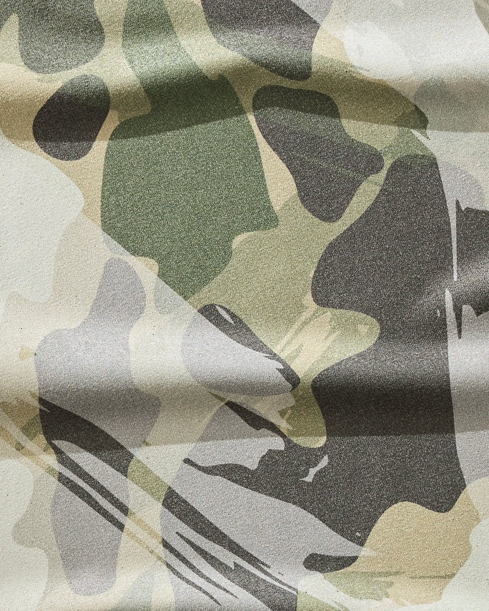 A close-up of GEOMETRY's Wildscape fitness towel, featuring ultra-absorbent, recycled fabric with a green, beige, brown, and gray camouflage pattern of irregular shapes and textured appearance.