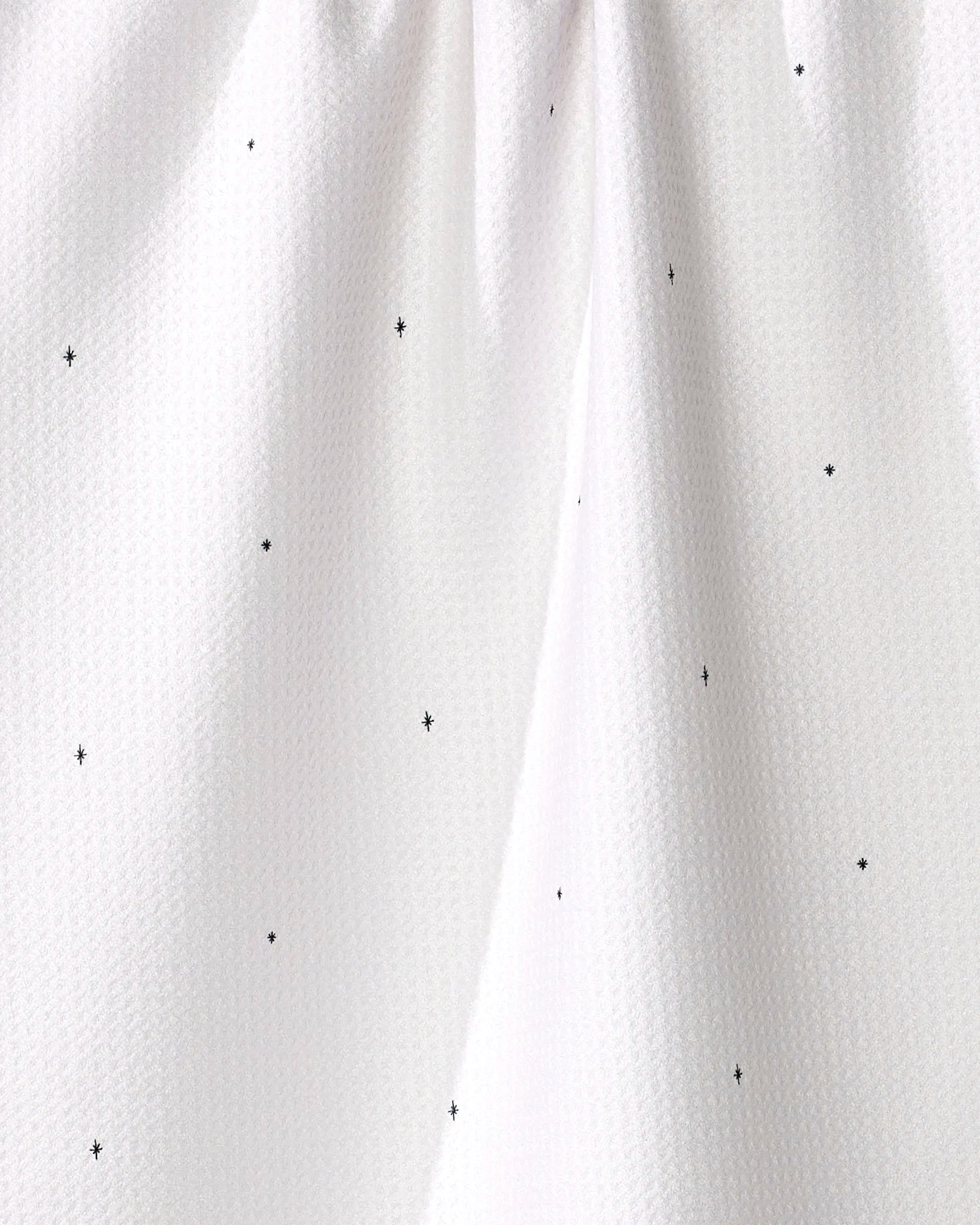 Close-up of the Kailee Wright "Jingle All the Way" white tea towel, crafted from recycled materials with small black polka dots and gentle top gathers.