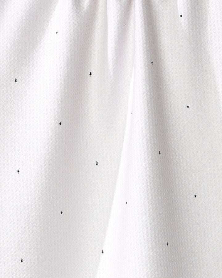 Close-up of the Kailee Wright "Jingle All the Way" white tea towel, crafted from recycled materials with small black polka dots and gentle top gathers.