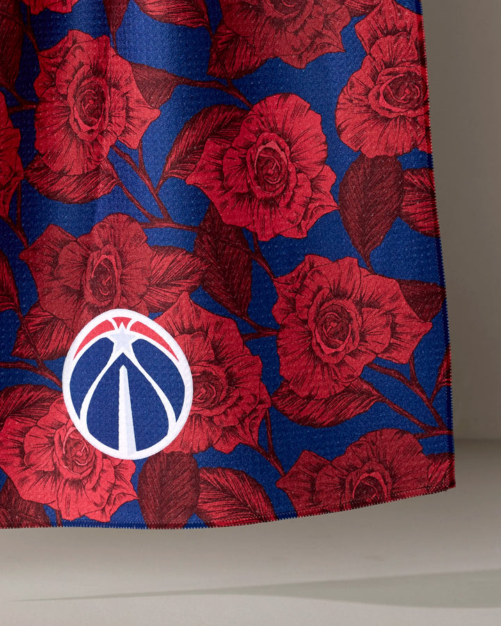The Wizards Floral tea towel by NBALAB x Geometry features blue fabric with red roses and a white and red basketball emblem resembling the Washington Wizards logo—an ideal, officially licensed NBA accessory for fans.