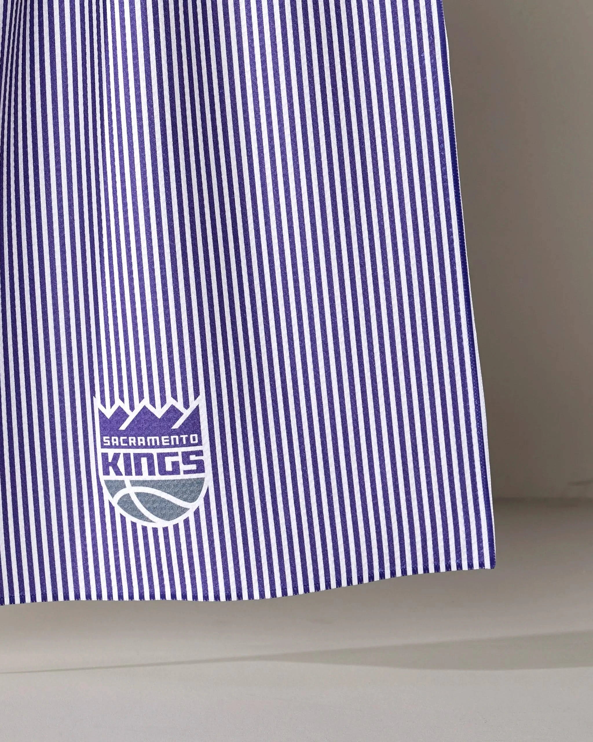 The Kings Classic by NBALAB x Geometry is a sustainable kitchen towel with vertical purple and white stripes and the Sacramento Kings logo—perfect for NBA fans.