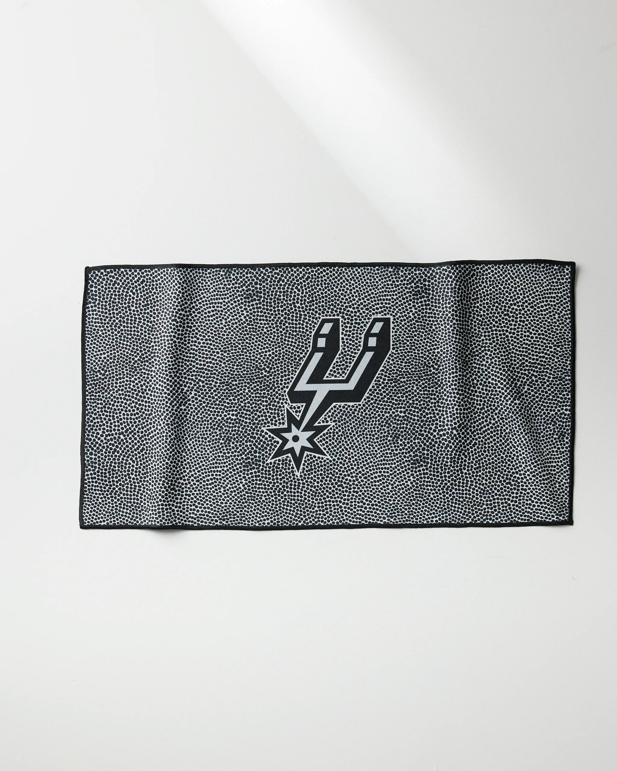 The NBALAB x Geometry Spurs Grip is a rectangular black and white fitness towel with a dotted pattern, black border, and the San Antonio Spurs logo centered—ideal as a quick-drying gym accessory.