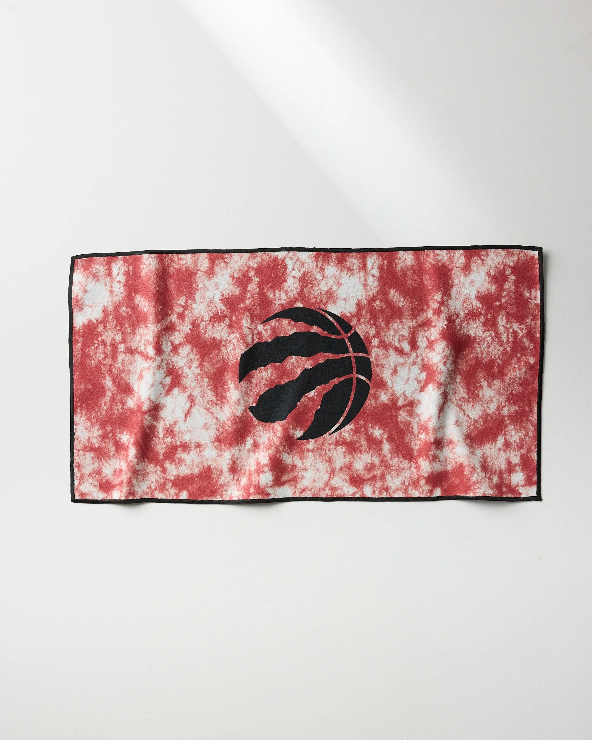 The Raptors Flash fitness towel by NBALAB x Geometry features a red and white tie-dye design with a black outline and a central black basketball logo with claw marks, shown laid flat on a white surface.