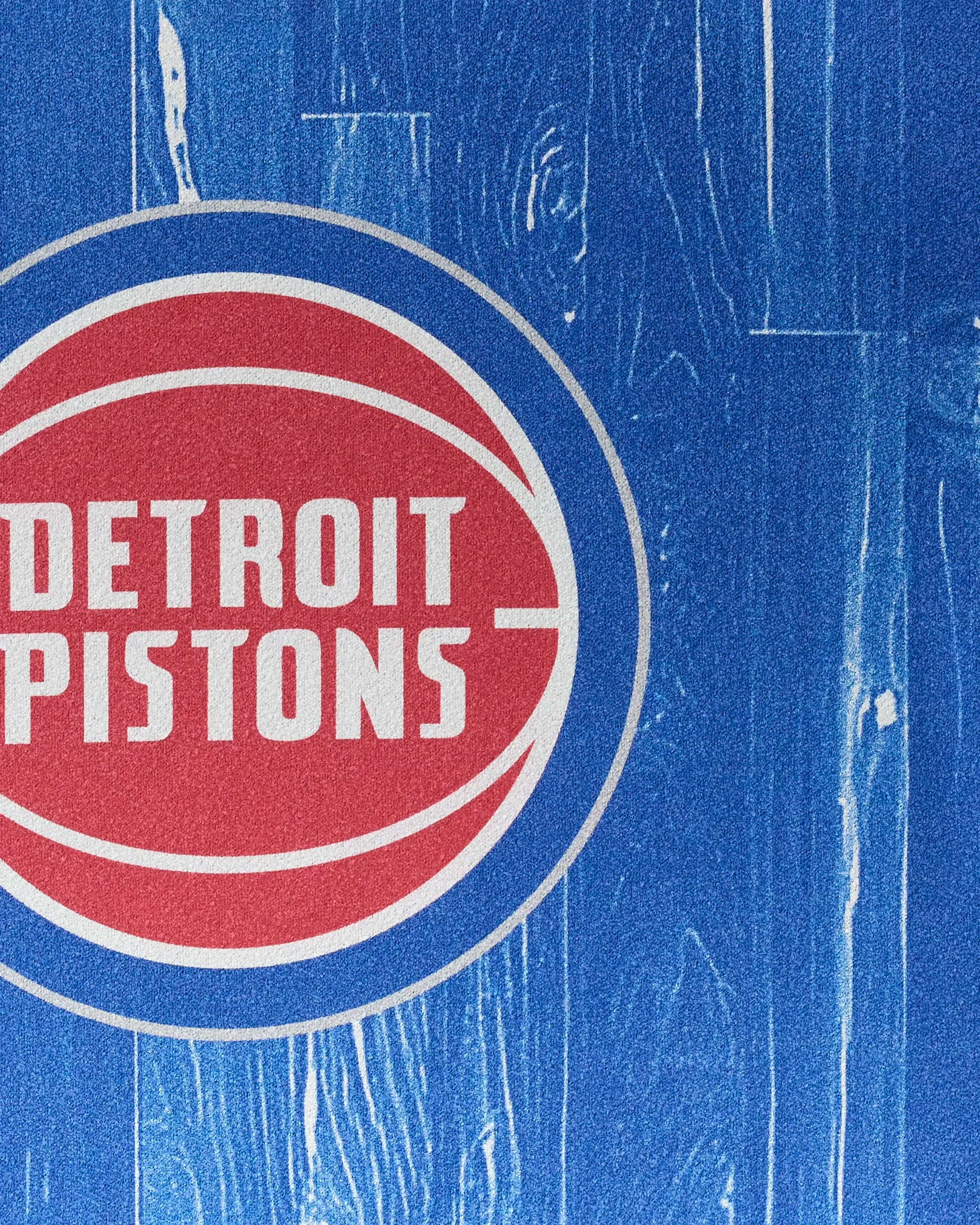 The Pistons Zone towel by NBALAB x Geometry showcases the Detroit Pistons’ white and red logo on a blue wood-textured background—ideal as a sustainable, NBA-themed workout or fitness accessory.