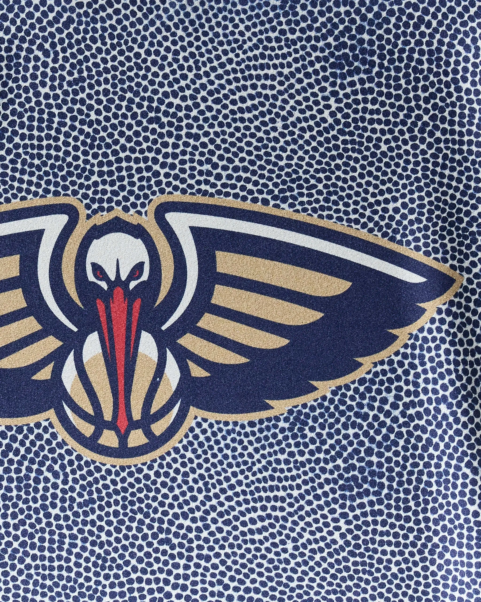 The NBALAB x Geometry Pelicans Grip gym towel features a stylized pelican logo with outstretched wings in navy, gold, red, and white on a dotted blue and white background. Its quick-drying fabric is perfect for workouts.