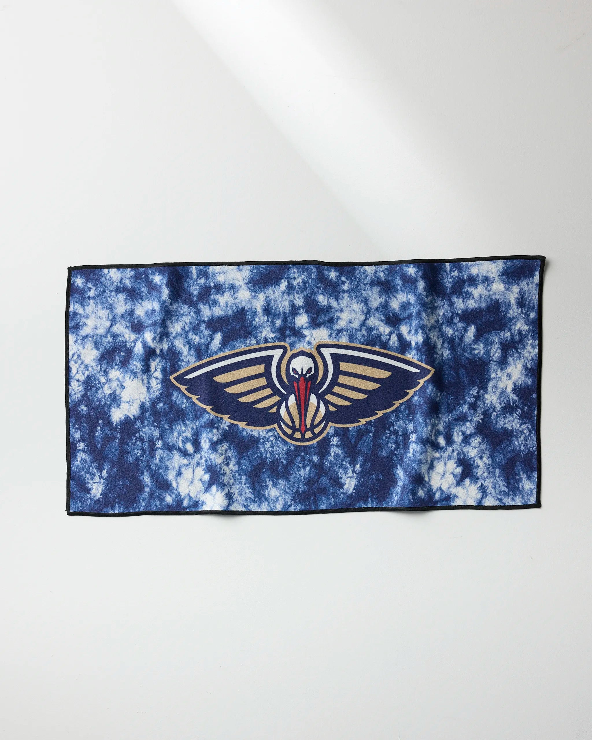 The Pelicans Flash by NBALAB x Geometry is a blue and white tie-dye NBA fitness towel featuring the New Orleans Pelicans logo with outstretched wings, centered on a quick-drying rectangular cloth.